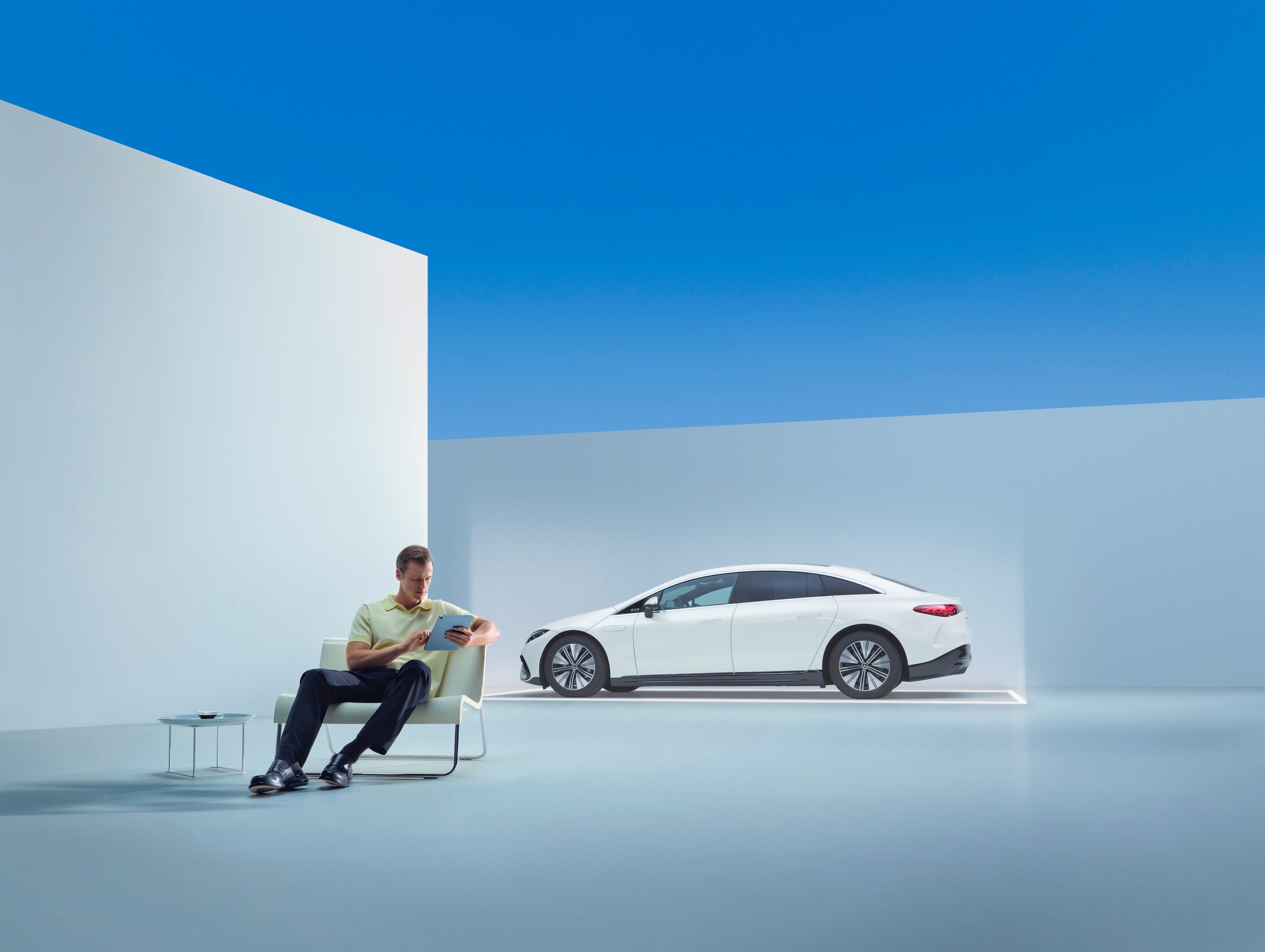 Um homem sentado diante do seu Mercedes-Benz, com o smartphone na mão.