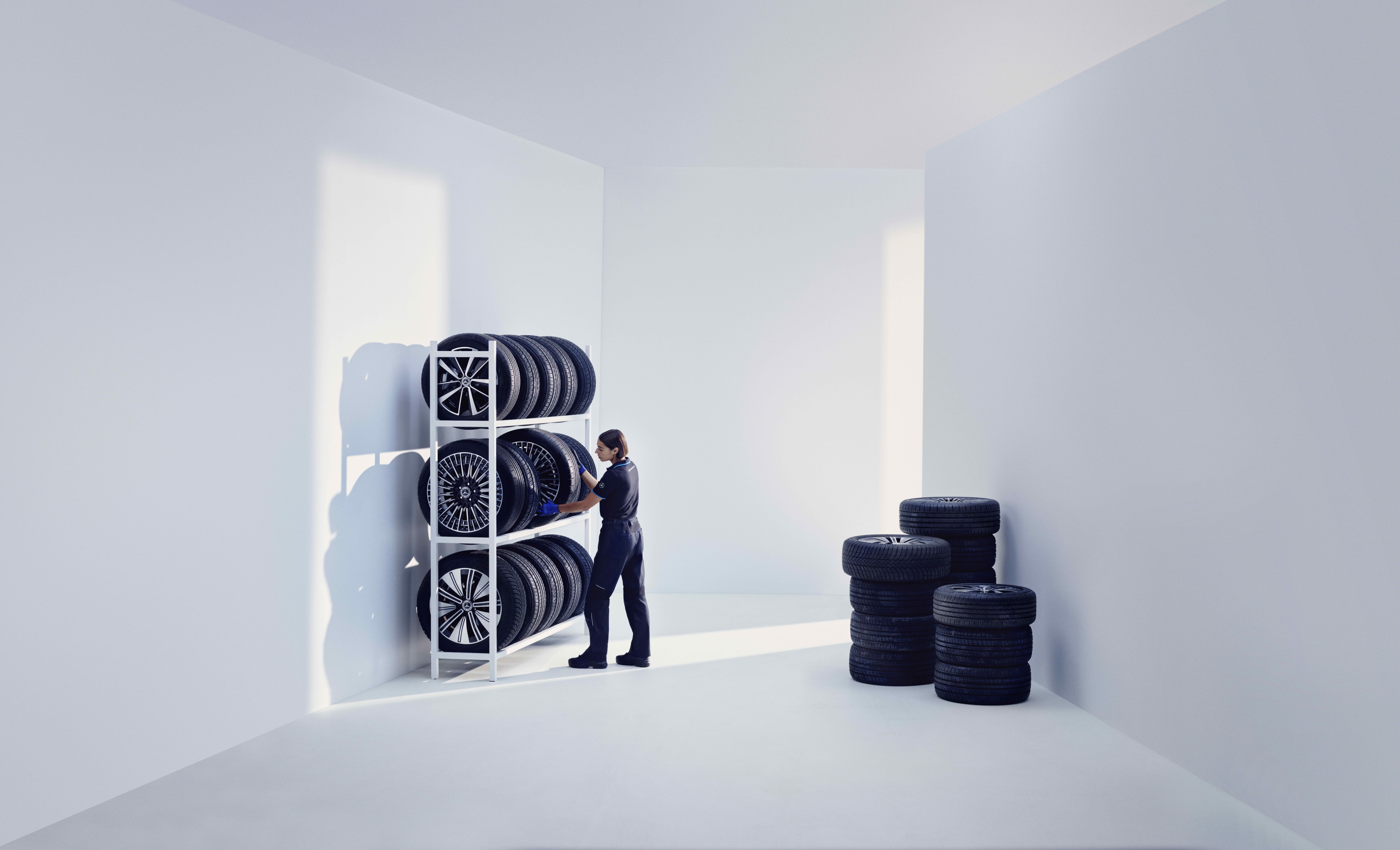 Pneus originais | Mercedes-Benz Um técnico da Mercedes-Benz guarda os pneus originais Mercedes-Benz numa prateleira.