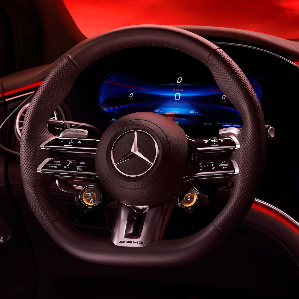 Vista do volante AMG Performance, a partir do banco do condutor, sobre um fundo vermelho.