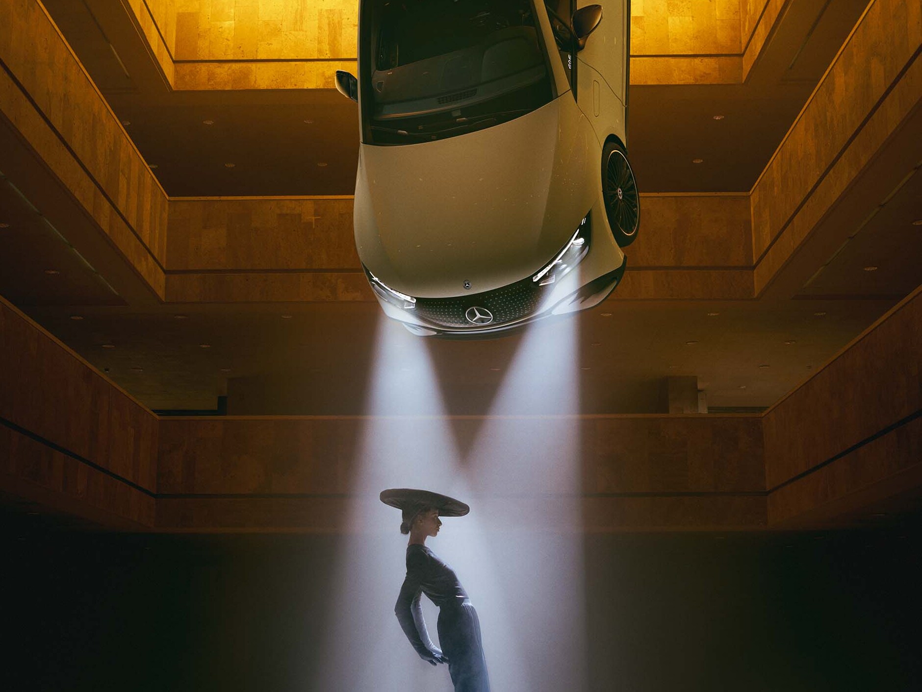 Um espaço escuro com faróis pendurados no teto, em cujo feixe de luz se encontra uma mulher.