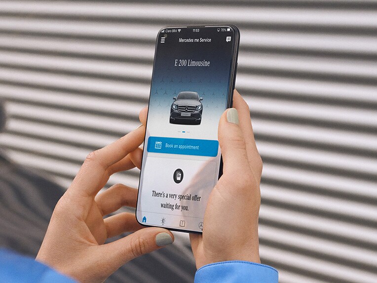 Um smartphone e uma vista detalhada dos faróis de um veículo Mercedes-Benz.
