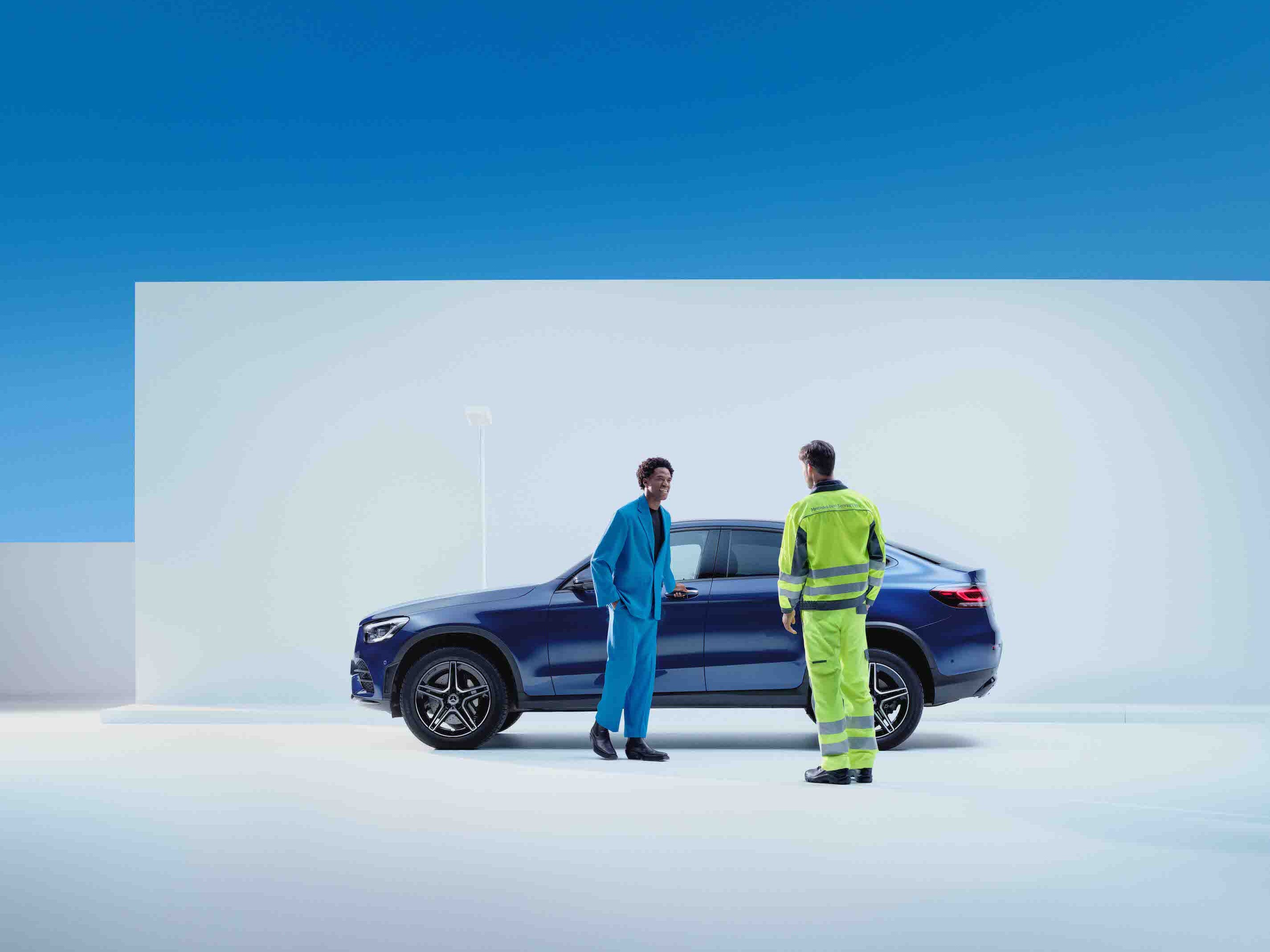 Um homem está com um colaborador de serviço em frente a um Mercedes-Benz.