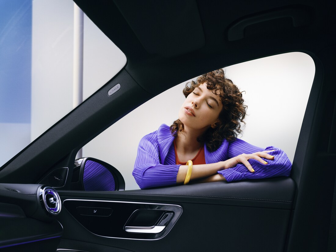 Uma mulher aprecia o seu Mercedes-Benz limpo.