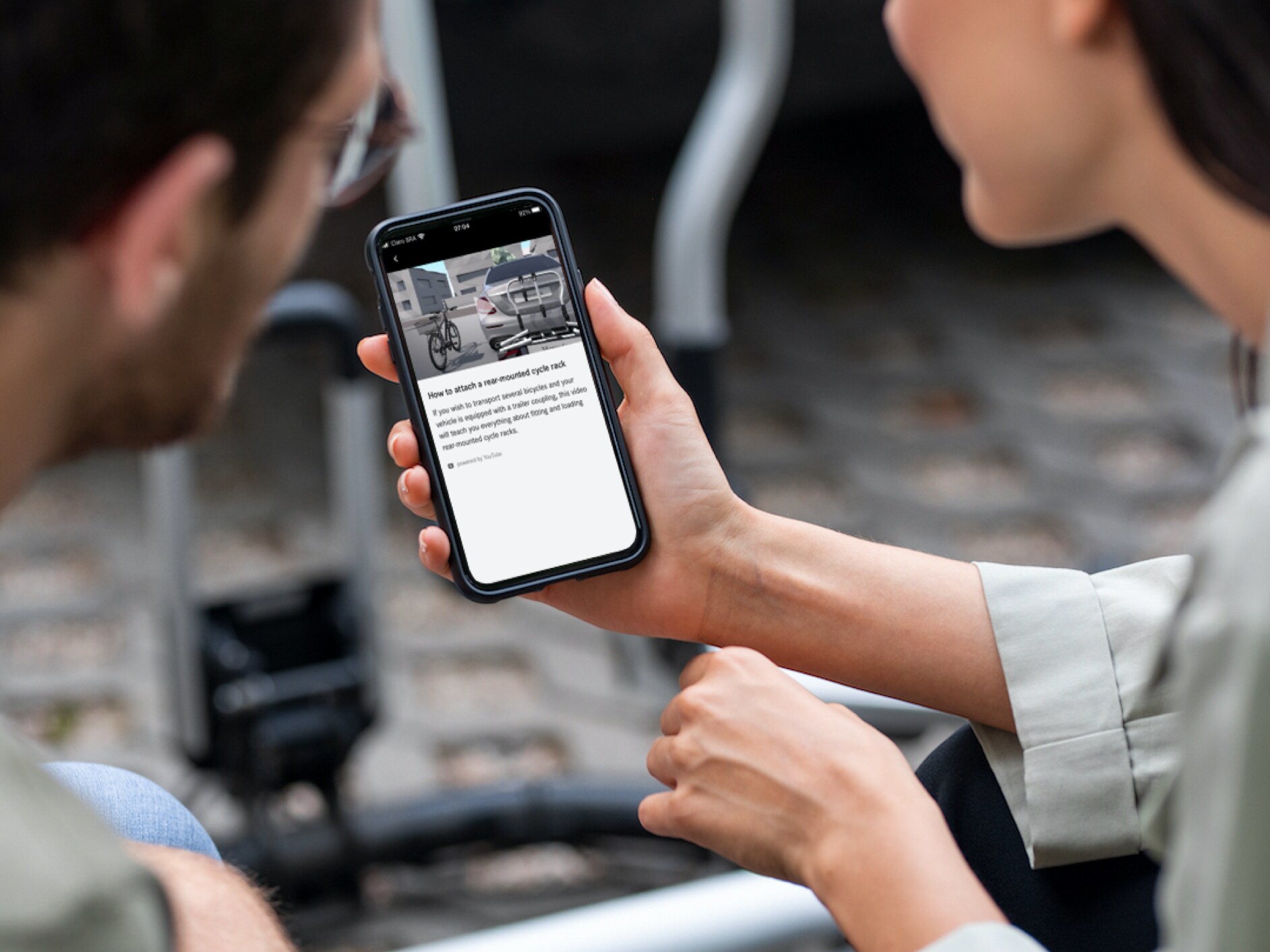 Um homem e uma mulher vêm vídeos explicativos Mercedes-Benz no smartphone.