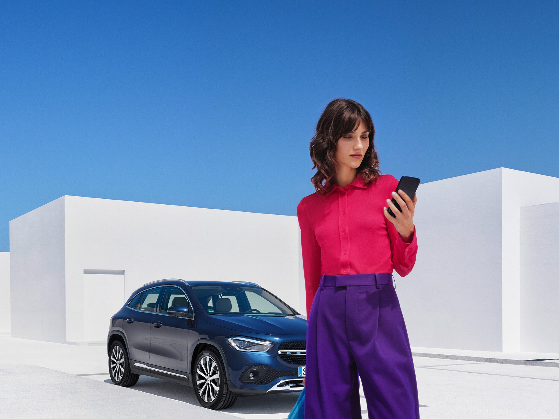 Uma mulher estabelece uma ligação com o seu Mercedes-Benz através da aplicação Mercedes me no seu smartphone.
