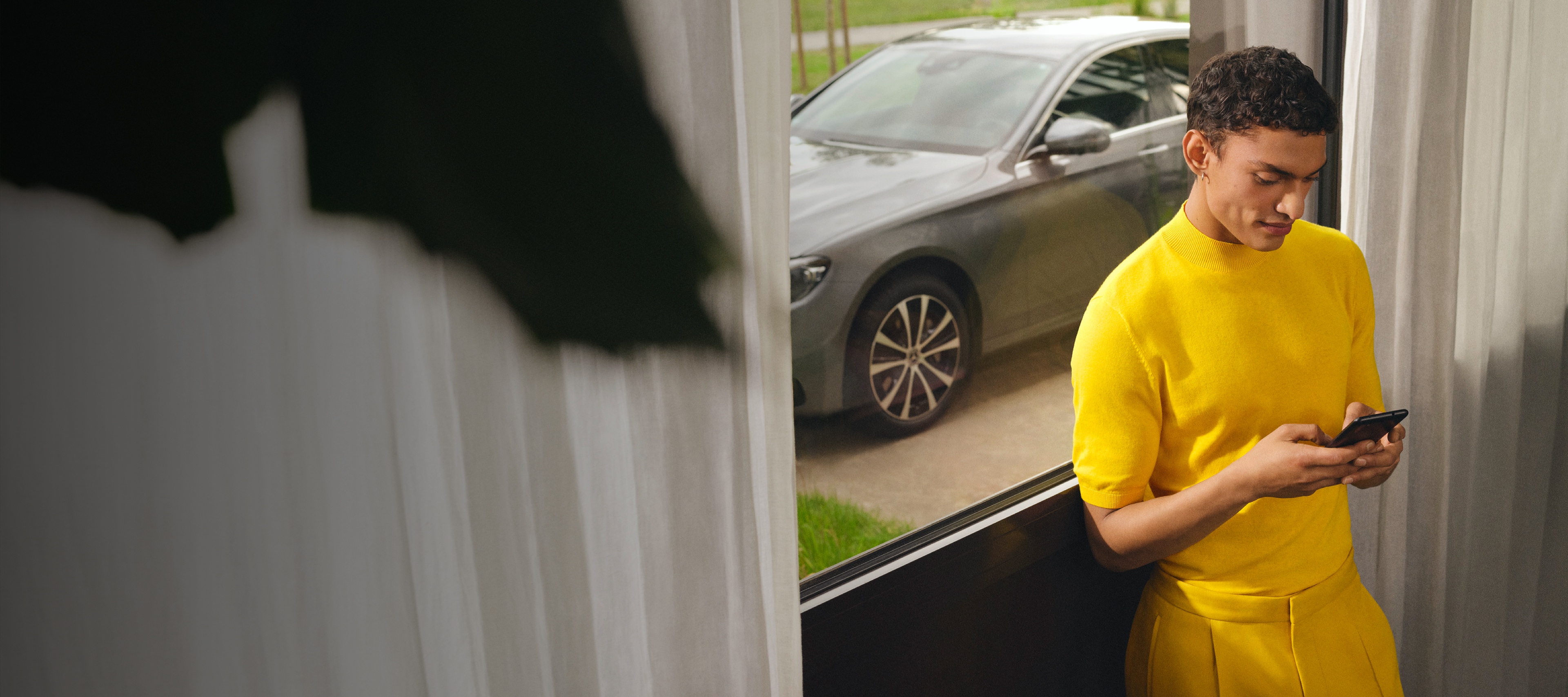 Um homem está ligado ao seu Mercedes-Benz através de extras digitais no smartphone. Um homem está ligado ao seu Mercedes-Benz através de extras digitais no smartphone.