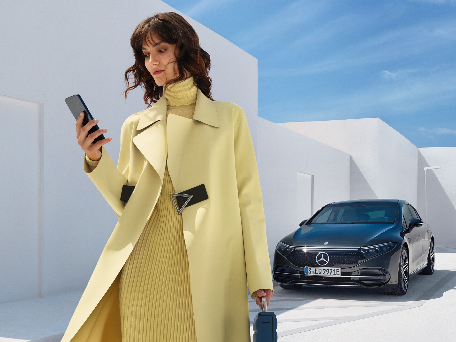 Uma mulher encontra-se em frente ao EQS Limousine da Mercedes-Benz.