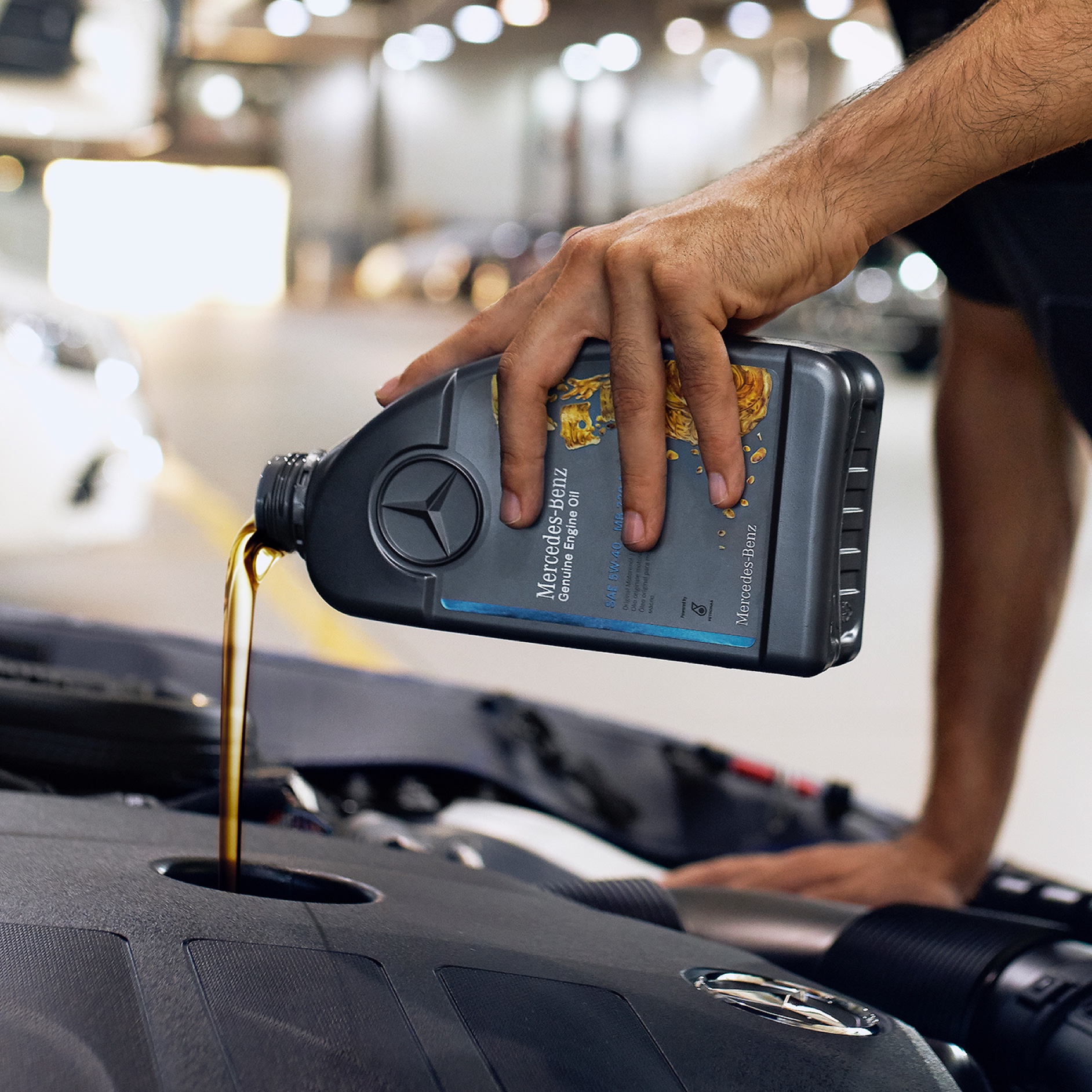 Óleo de motor | Mercedes-Benz Uma pessoa deita óleo de motor no veículo Mercedes-Benz.