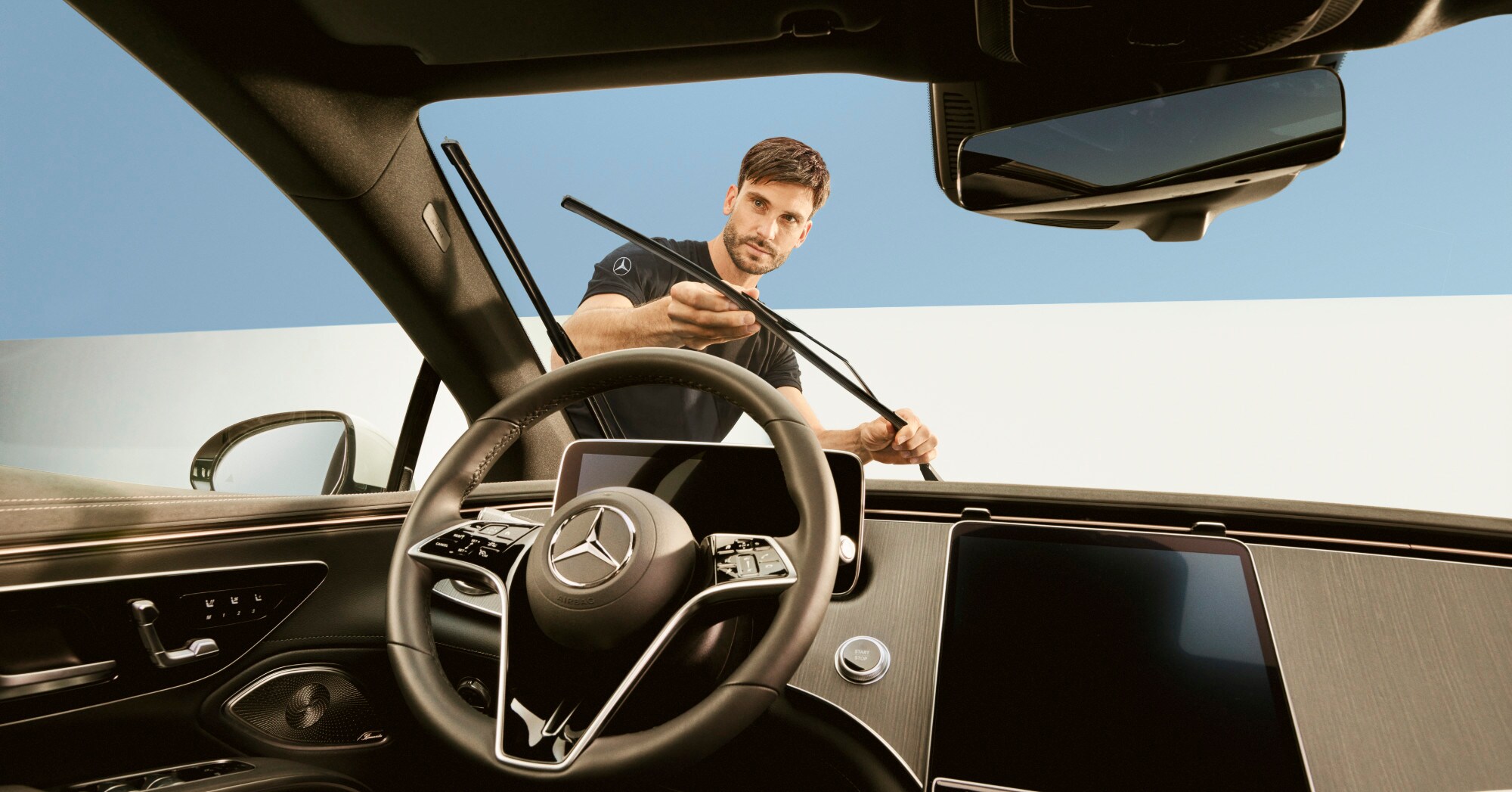 Um técnico a reparar as escovas do limpa-vidros de um veículo Mercedes-Benz.