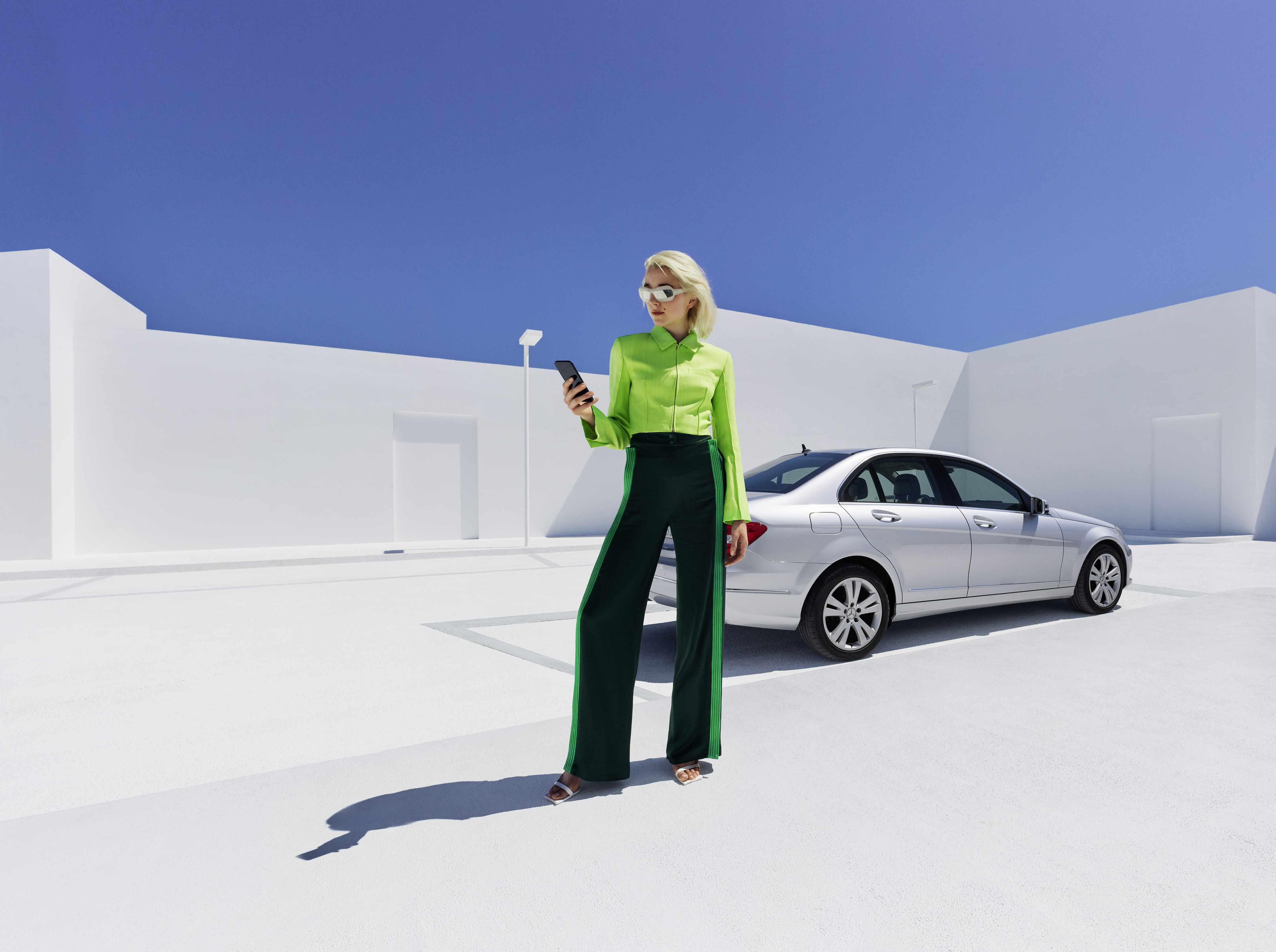 Tenha uma boa viagem com a garantia para veículos novos Mercedes-Benz. | Mercedes-Benz Uma mulher descontraída ao telemóvel em frente ao seu Mercedes.