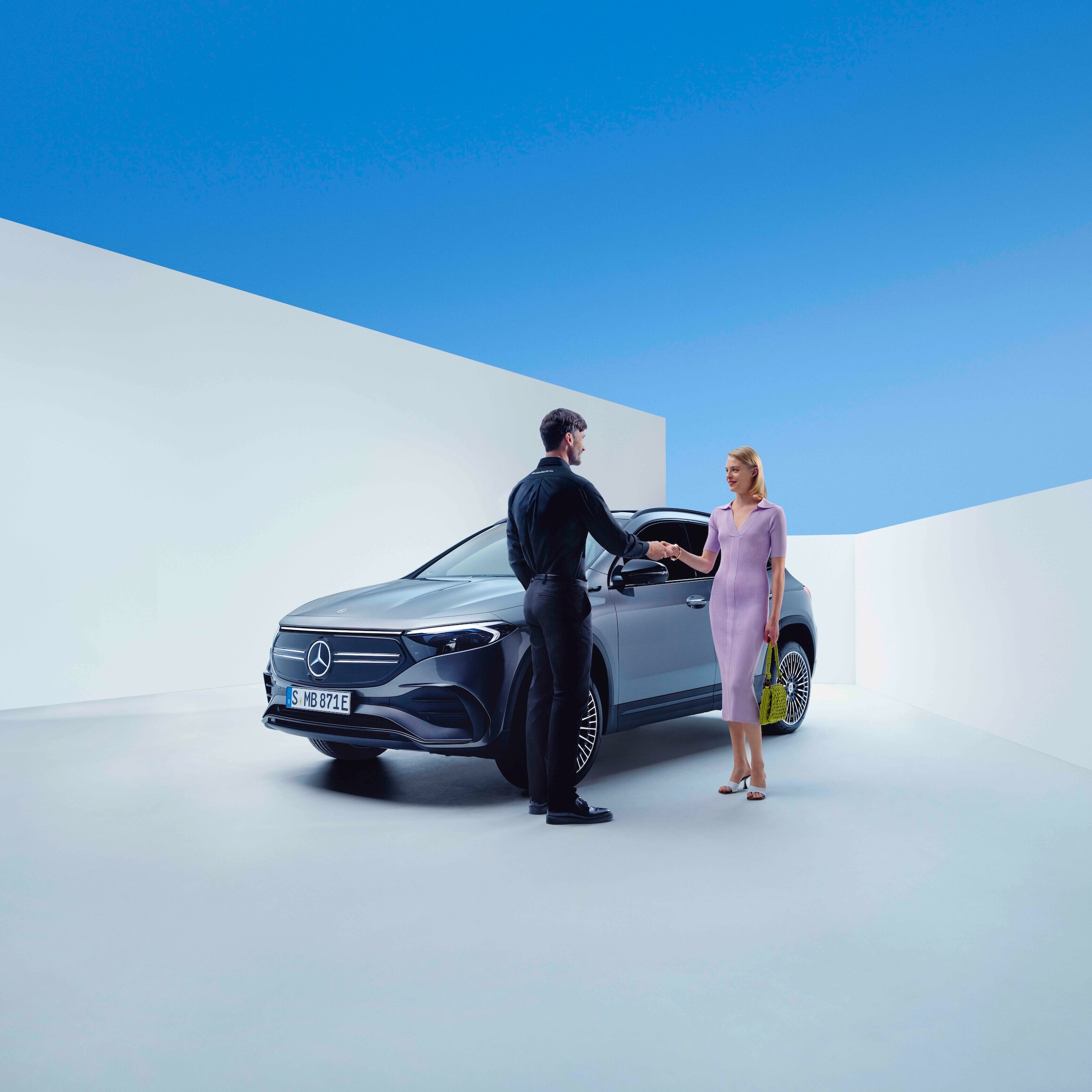 Um colaborador da Mercedes-Benz e uma mulher de mãos dadas em frente a um Mercedes-Benz