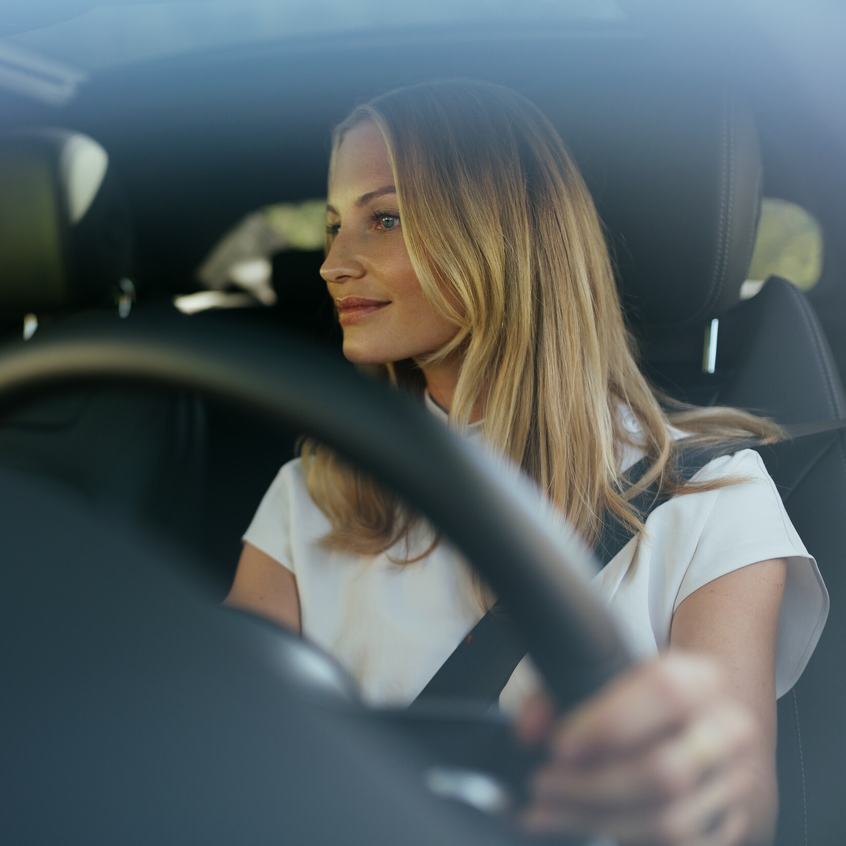 Uma mulher descontraída ao volante do seu Mercedes.