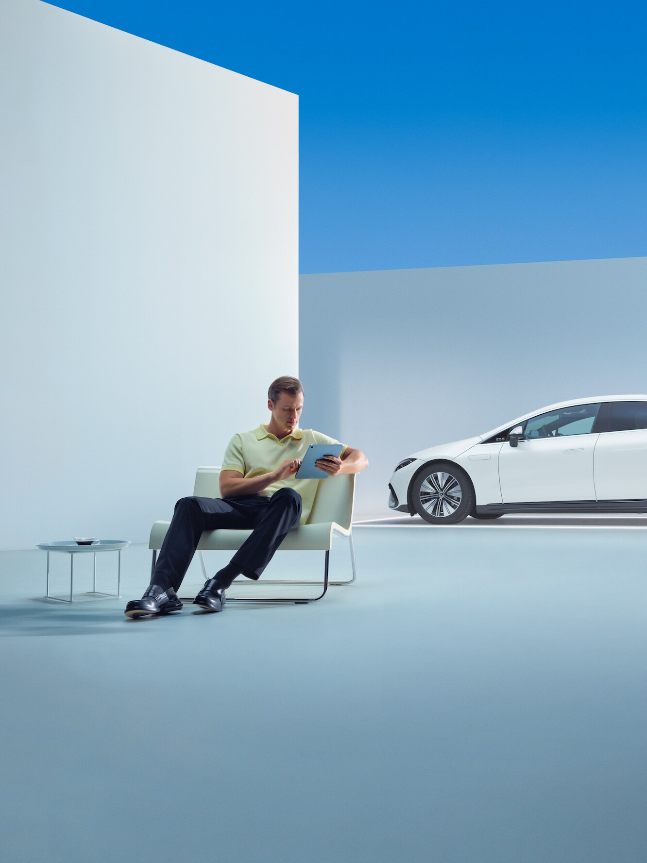 Um homem descontraído senta-se com o seu tablet em frente ao seu Mercedes.