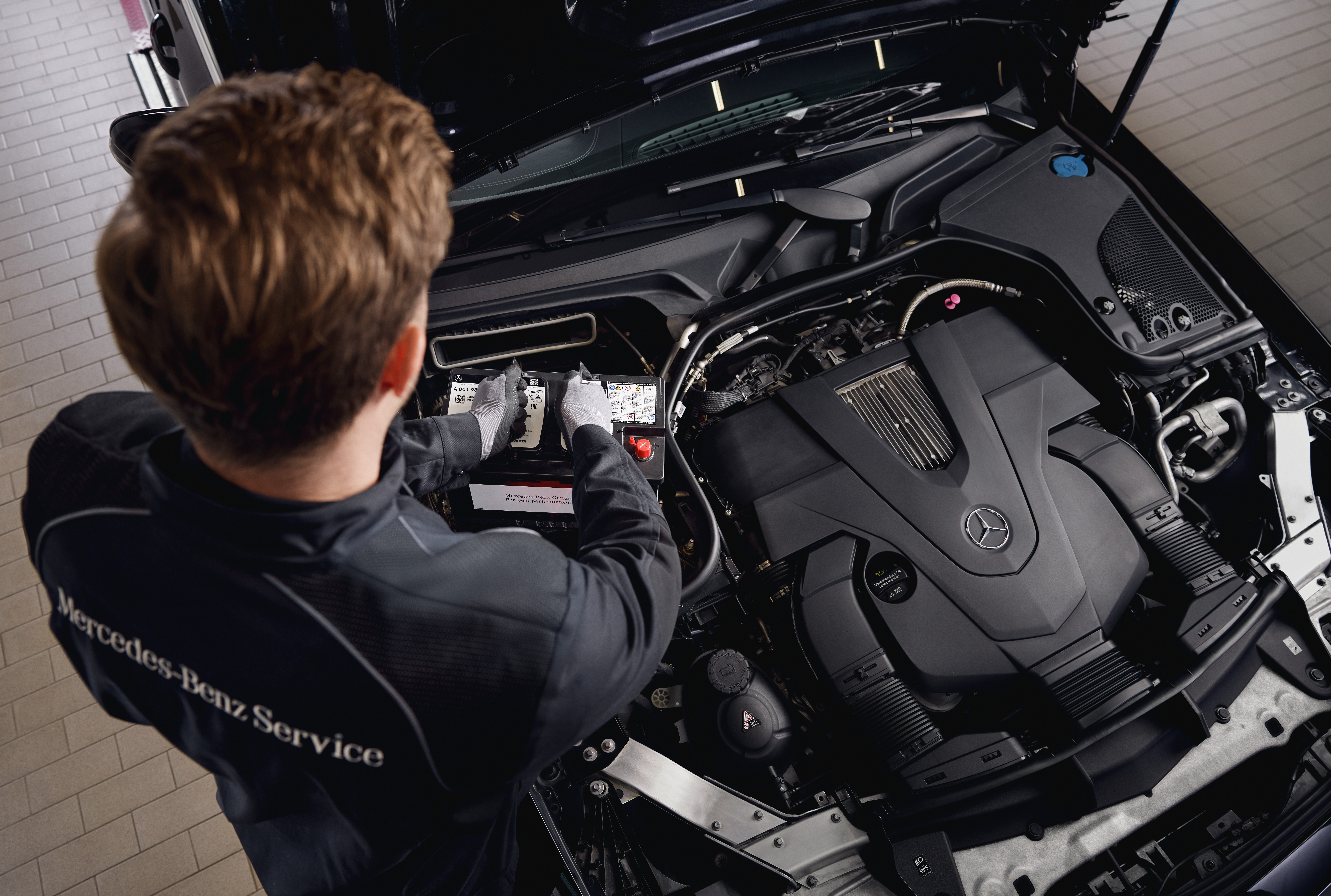 Baterias do motor de arranque originais Mercedes-Benz Serviço de motor numa oficina, mostrando a substituição de componentes utilizando peças originais Mercedes-Benz.