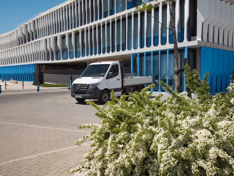 O Mercedes-Benz eSprinter Chassis como veículo de plataforma estacionado em frente a um edifício.