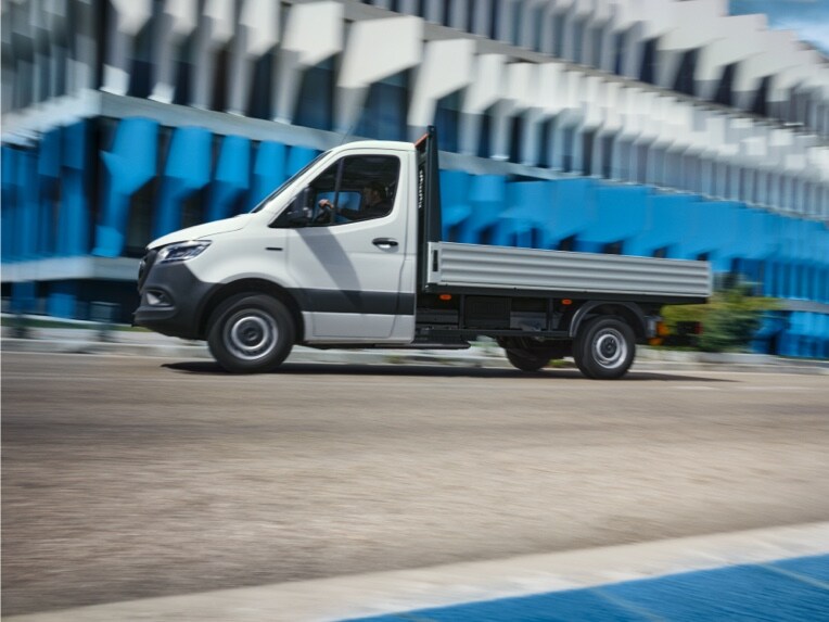 O Mercedes-Benz eSprinter Chassis como veículo de plataforma a passar por um edifício.