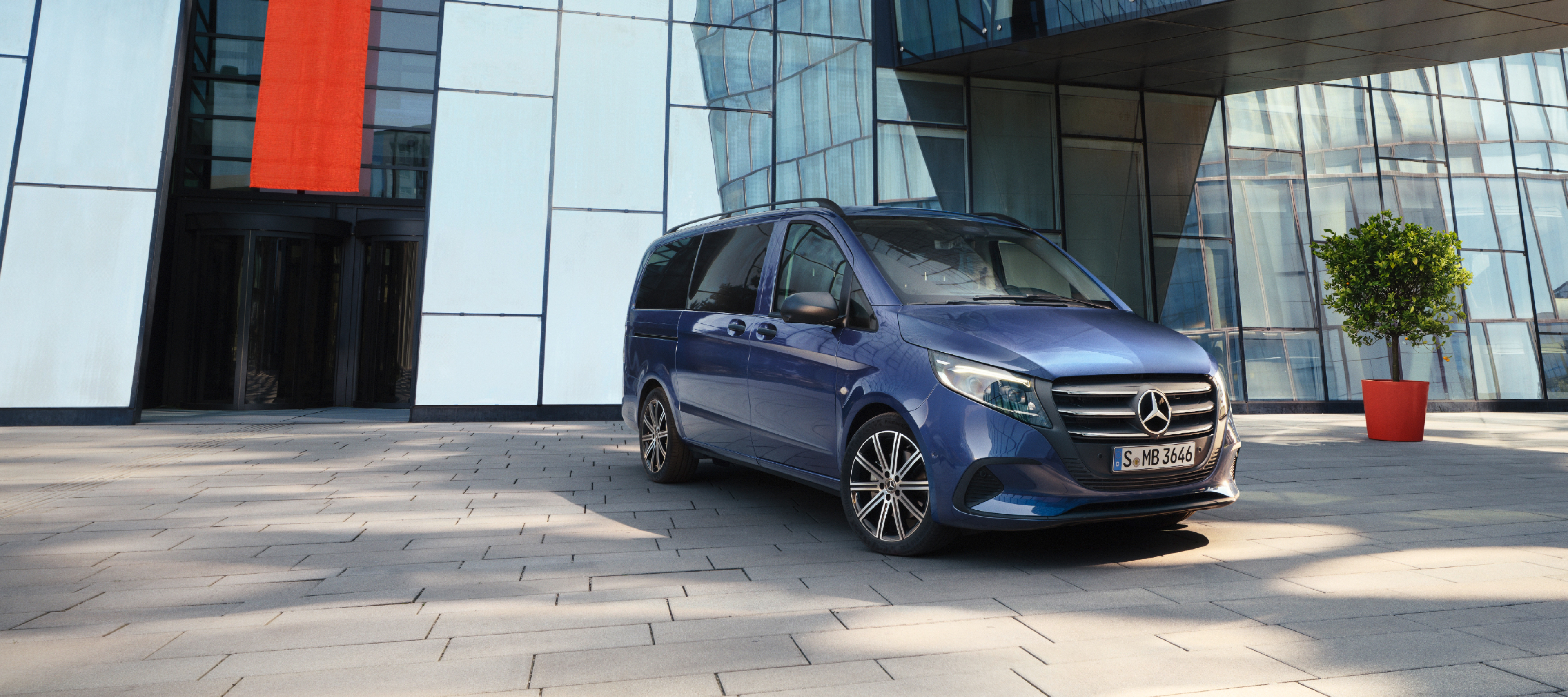 Comparação de veículos | Vito Tourer | Mercedes-Benz O Mercedes-Benz Vito Tourer em frente a um edifício de escritórios.