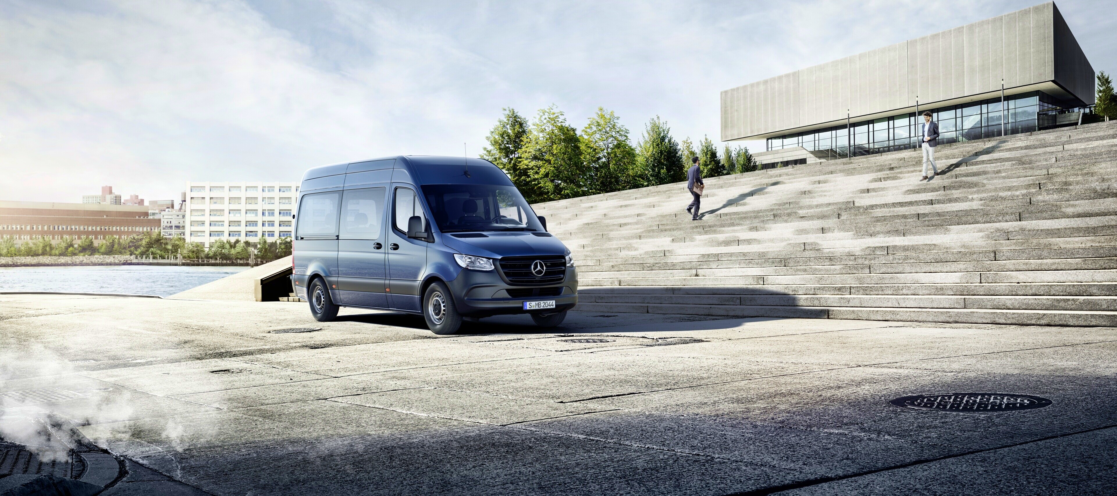 Comparação de veículos | Sprinter Tourer | Mercedes-Benz O Mercedes-Benz Sprinter Tourer em frente a um edifício.