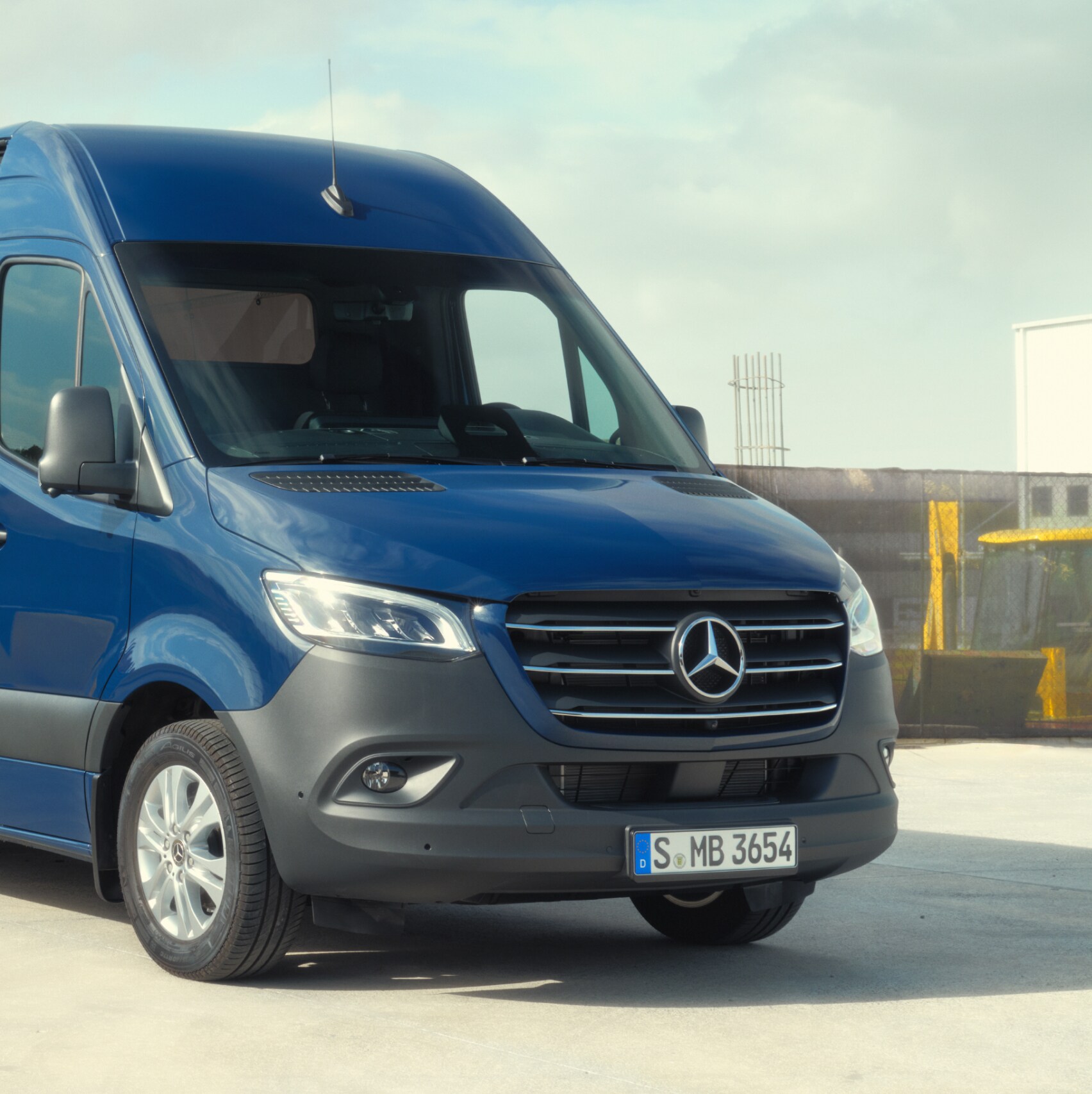 O Sprinter Furgão da Mercedes-Benz em frente a materiais de construção.