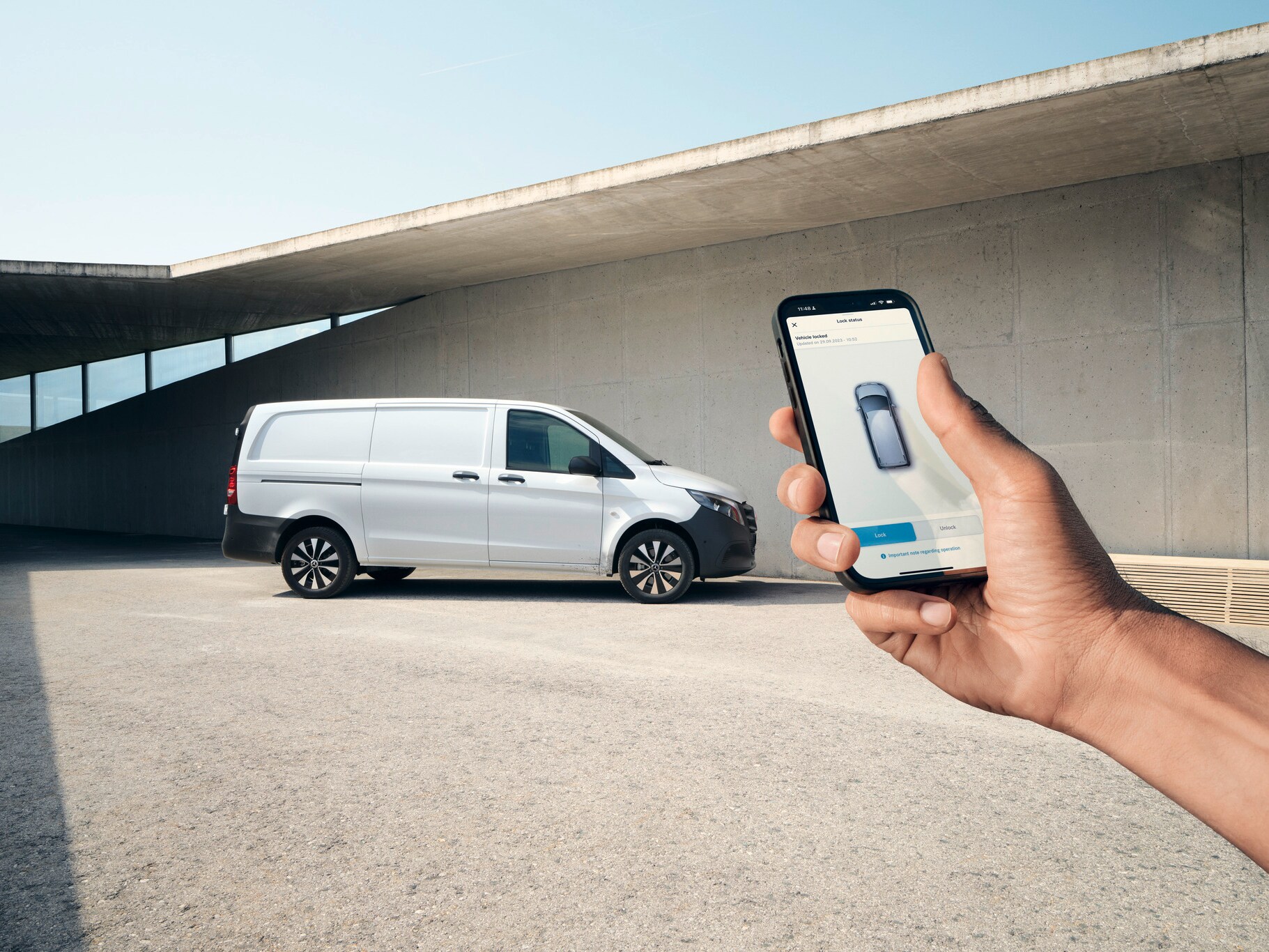 Uma mão a segurar um smartphone que exibe a aplicação Mercedes me. O Vito Furgão em segundo plano.