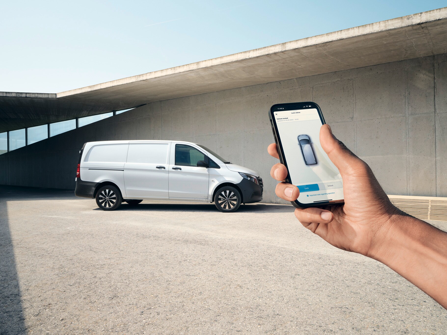 Uma mão a segurar um smartphone que exibe a aplicação Mercedes me. O Vito Furgão em segundo plano.