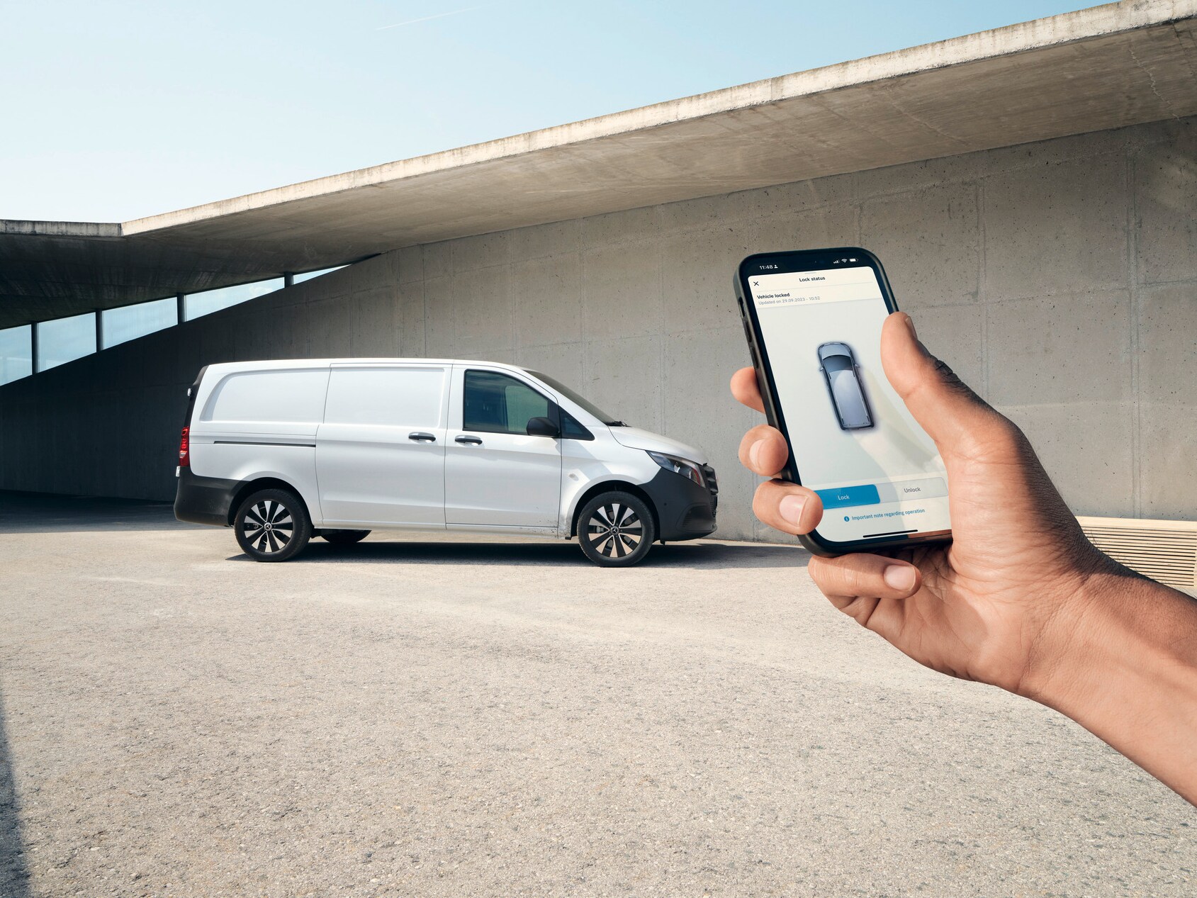 Uma mão a segurar um smartphone que exibe a aplicação Mercedes me. O Vito Furgão em segundo plano.
