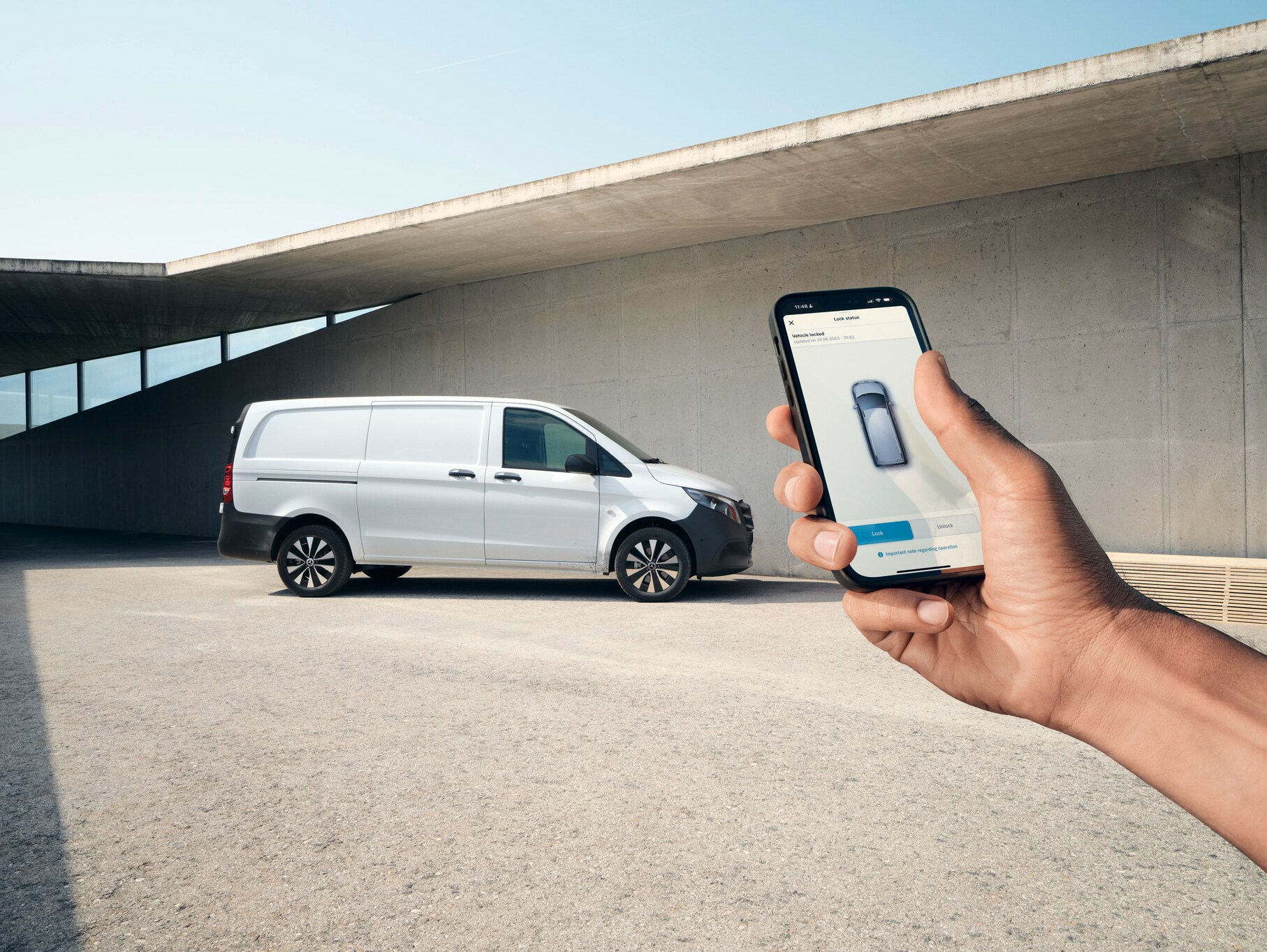 Uma mão a segurar um smartphone que exibe a aplicação Mercedes me. O Vito Furgão em segundo plano.