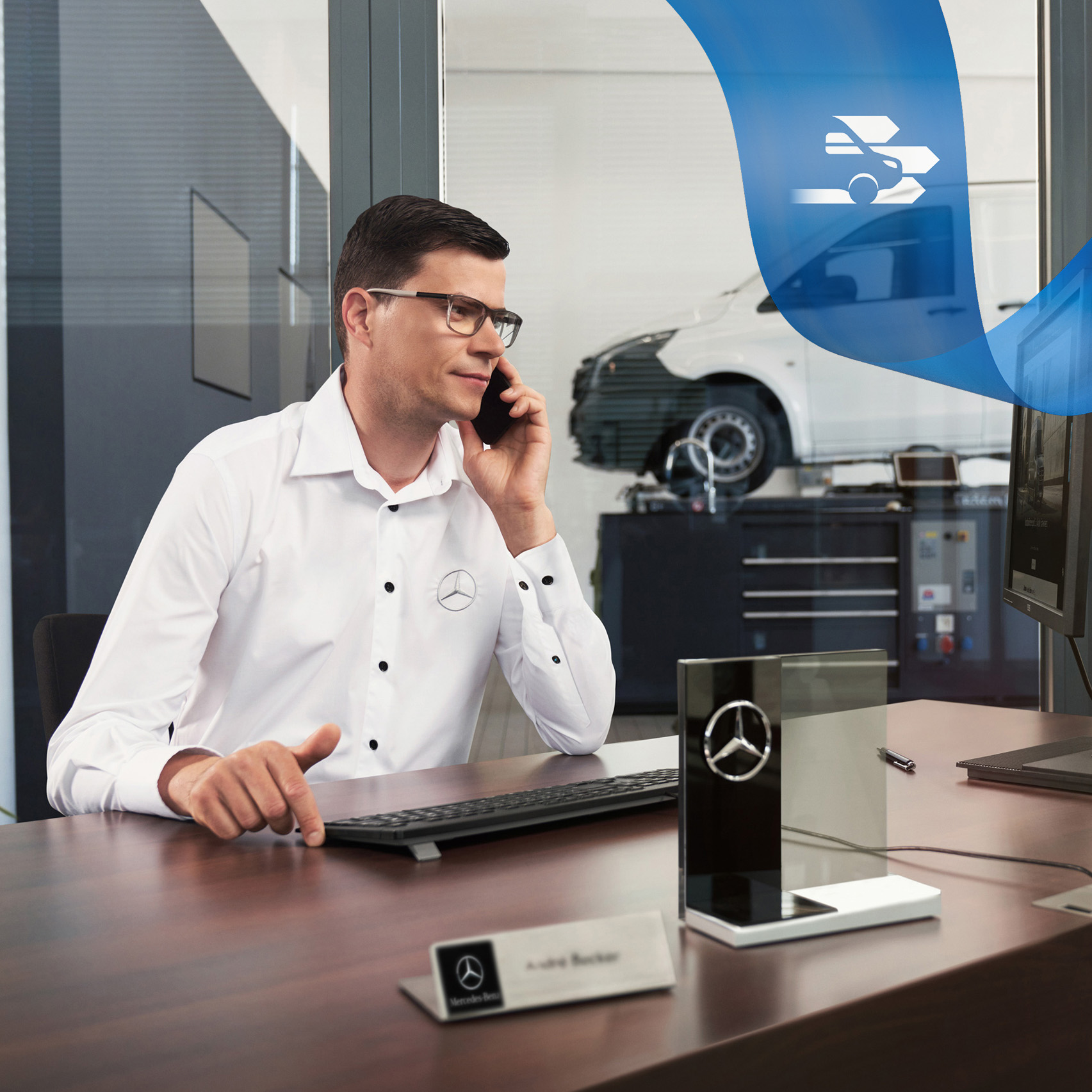 Mercedes-Benz | Assistência de veículos comerciais ligeiros | Assistência em Viagem Um funcionário numa secretária fala ao telefone com um veículo comercial ligeiro Mercedes-Benz Vito na oficina em segundo plano.