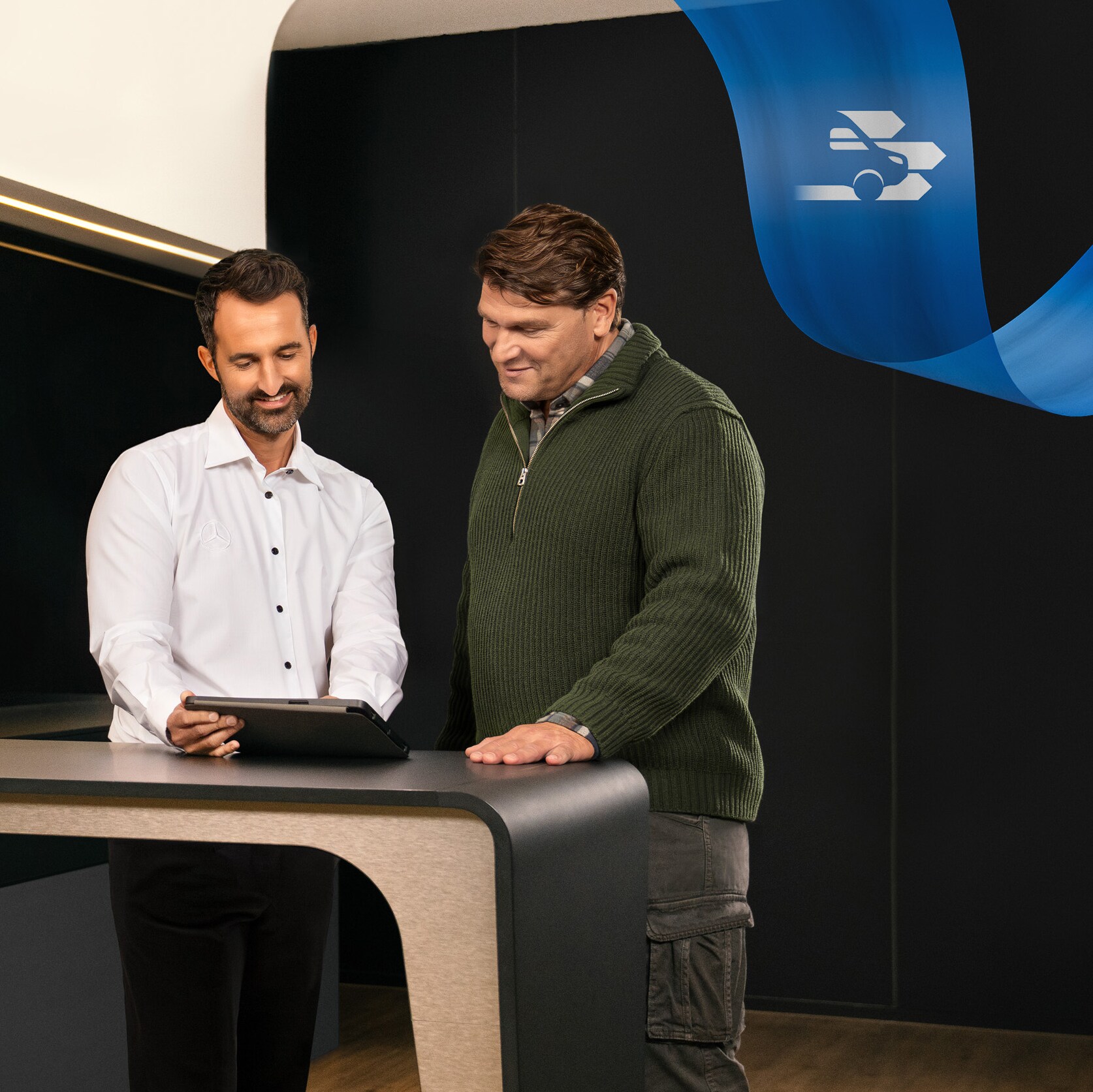 Dois homens de pé num escritório de uma Oficina Autorizada Mercedes-Benz, a falar sobre algo visto num tablet