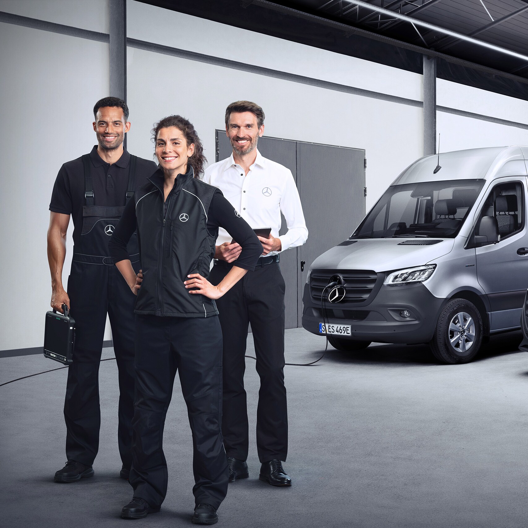 Três colegas da equipa Mercedes-Benz Service em frente a um Mercedes-Benz eSprinter e a um Mercedes-Benz eVito.