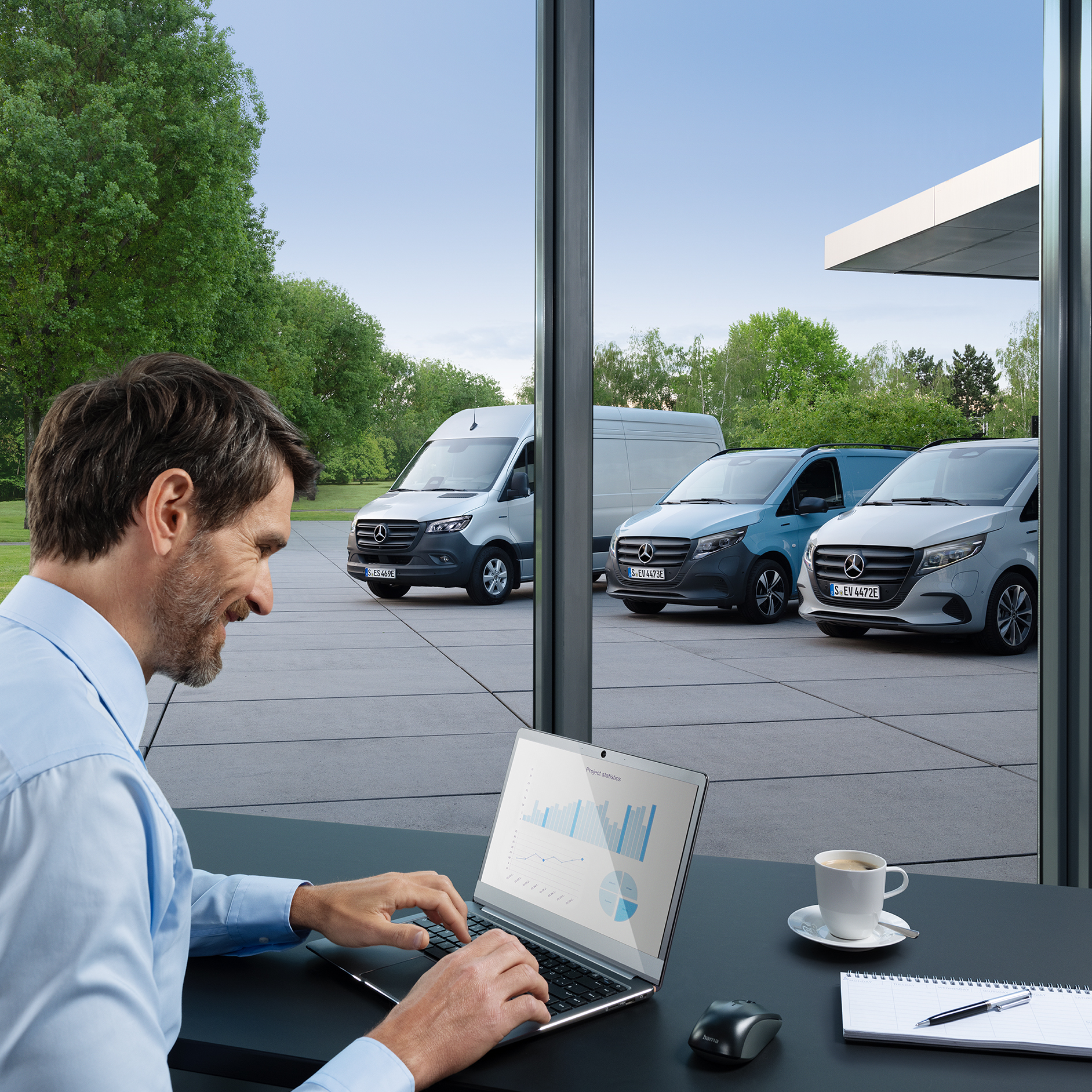 Veículos elétricos Mercedes-Benz | Mercedes-Benz ServiceCare Uma pessoa sentada em frente a um laptop num escritório. Três veículos comerciais ligeiros elétricos Mercedes-Benz estacionados no exterior.