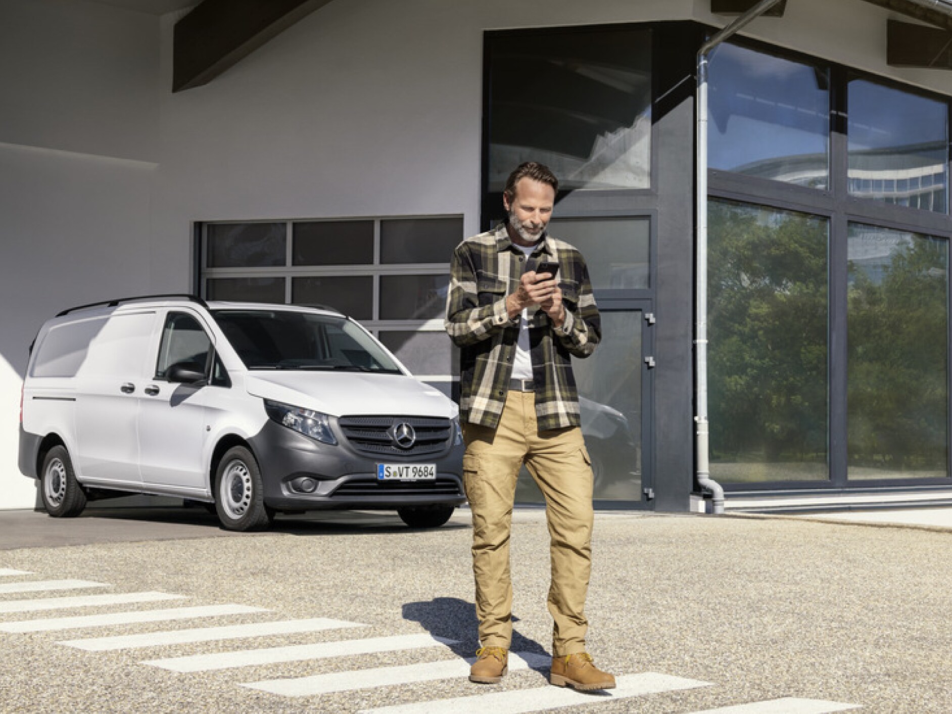 Uma pessoa com um smartphone em frente a um Mercedes-Benz Vito.