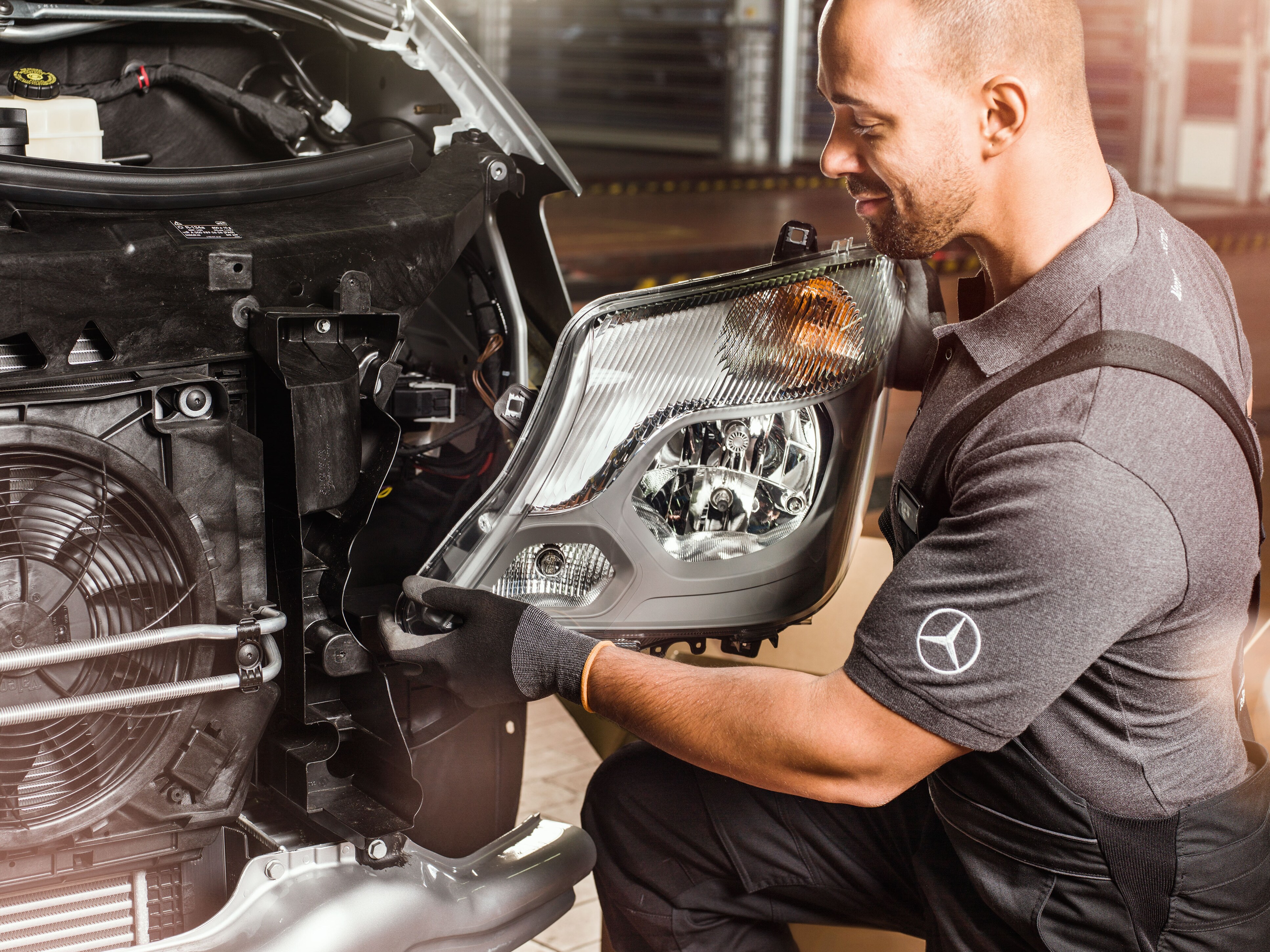 Mecânico a verificar as Peças Originais Mercedes-Benz em frente a um motor Sprinter aberto, de acordo com o catálogo de peças de substituição da Mercedes.