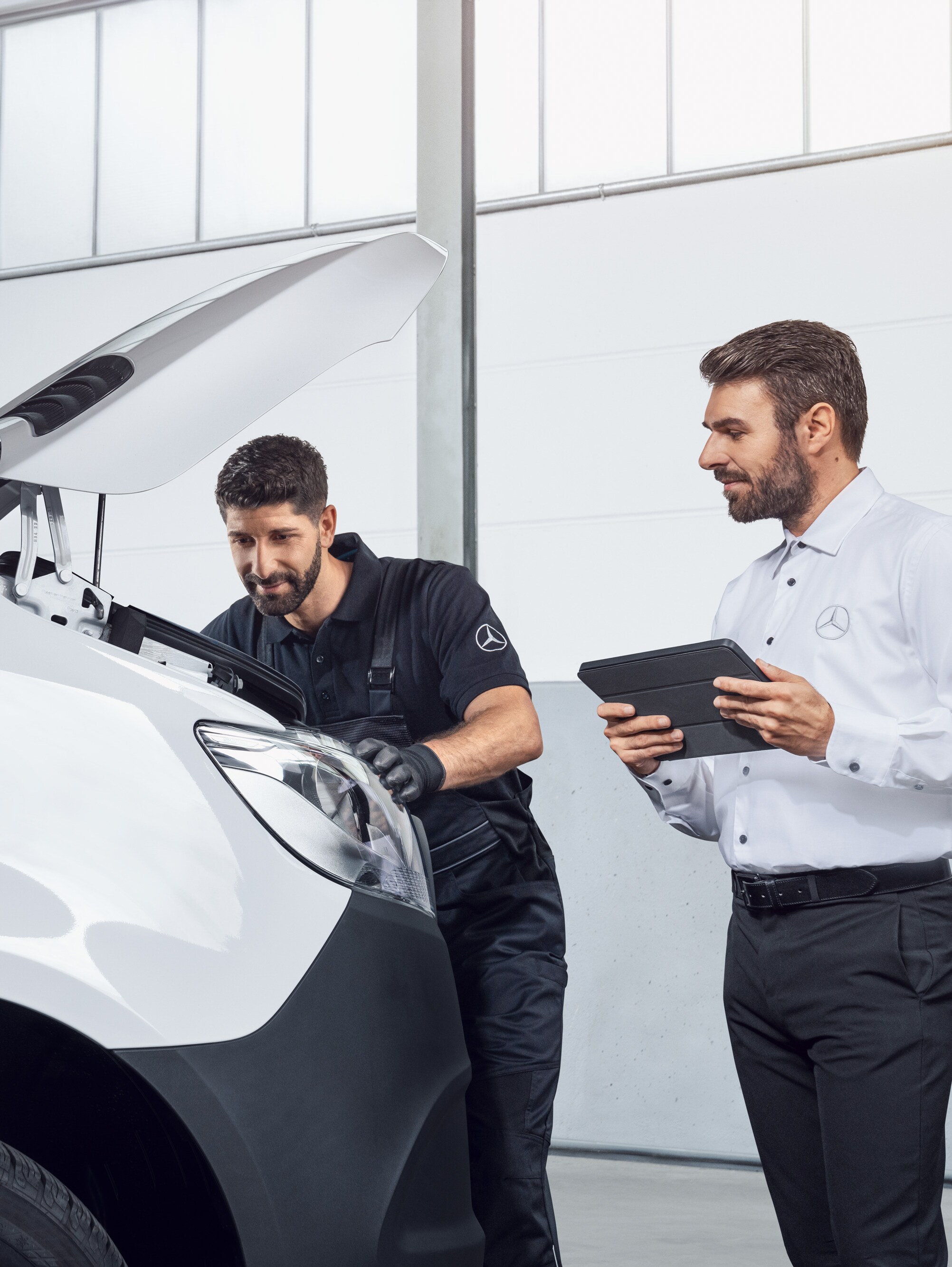 Dois homens a testar um Mercedes Sprinter com um tablet e o capot aberto, tema: peças de substituição Mercedes-Benz Sprinter.