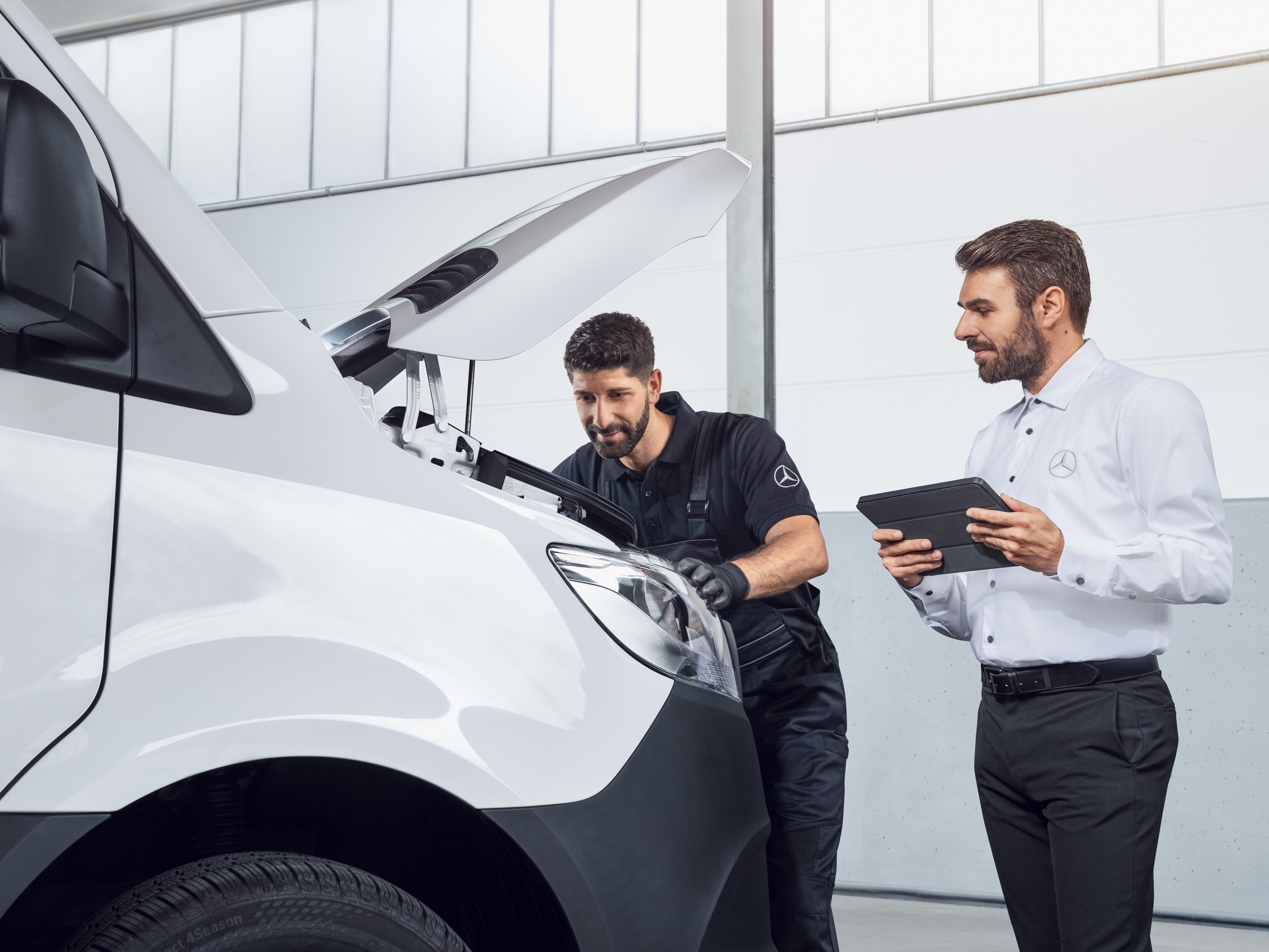 Dois homens a testar um Mercedes Sprinter com um tablet e o capot aberto, tema: peças de substituição Mercedes-Benz Sprinter.