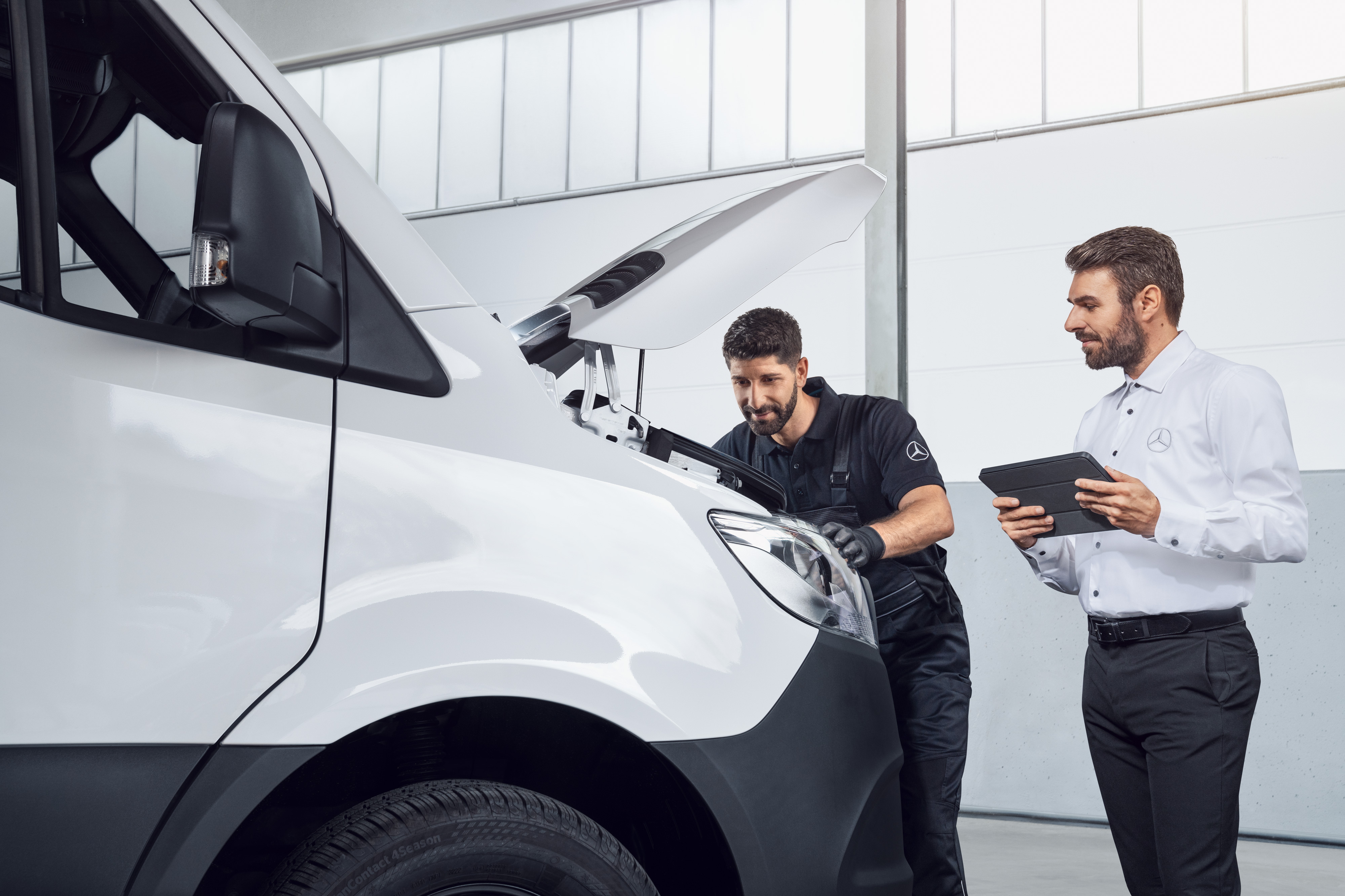 Mercedes-Benz | Carrinhas Peças Genuínas de Qualidade Dois homens a testar um Mercedes Sprinter com um tablet e o capot aberto, tema: peças de substituição Mercedes-Benz Sprinter.