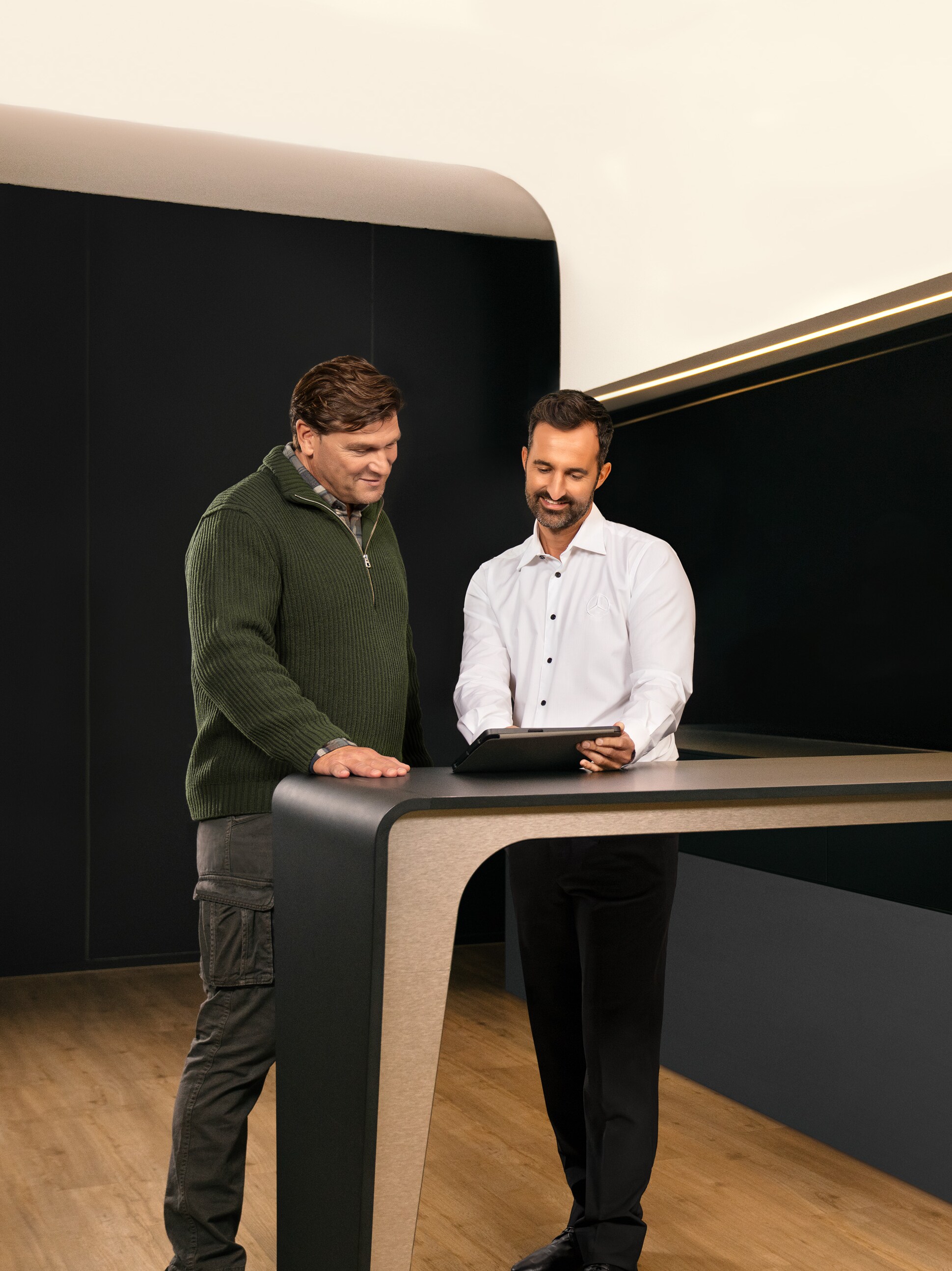 Dois homens discutem o serviço de veículos comerciais da Mercedes-Benz através de um tablet.