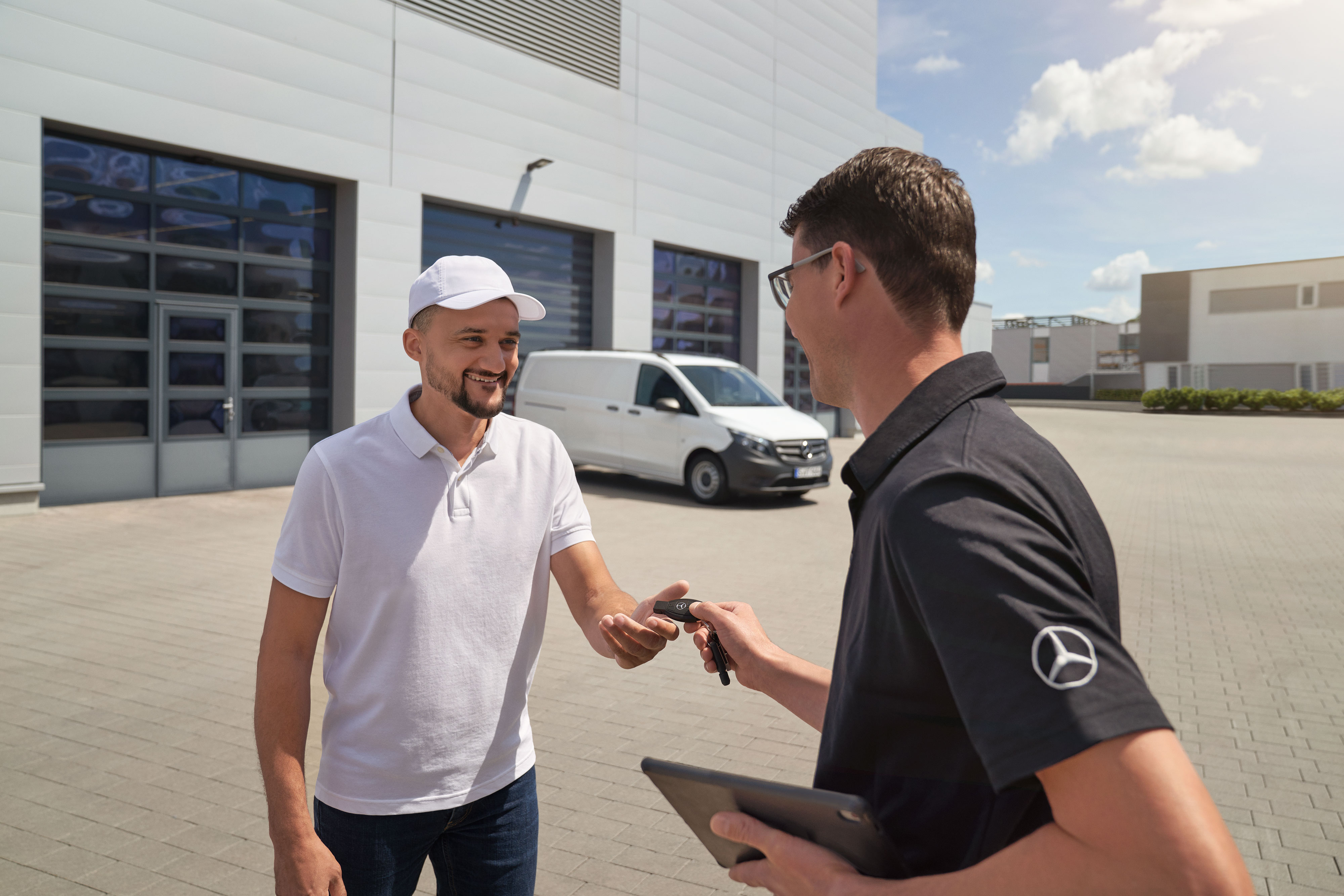 Mercedes-Benz | ServiceCare veículos comerciais ligeiros | Opções adicionais Um técnico a entregar o comando a um cliente com um veículo comercial ligeiro Mercedes-Benz Vito branco em segundo plano.