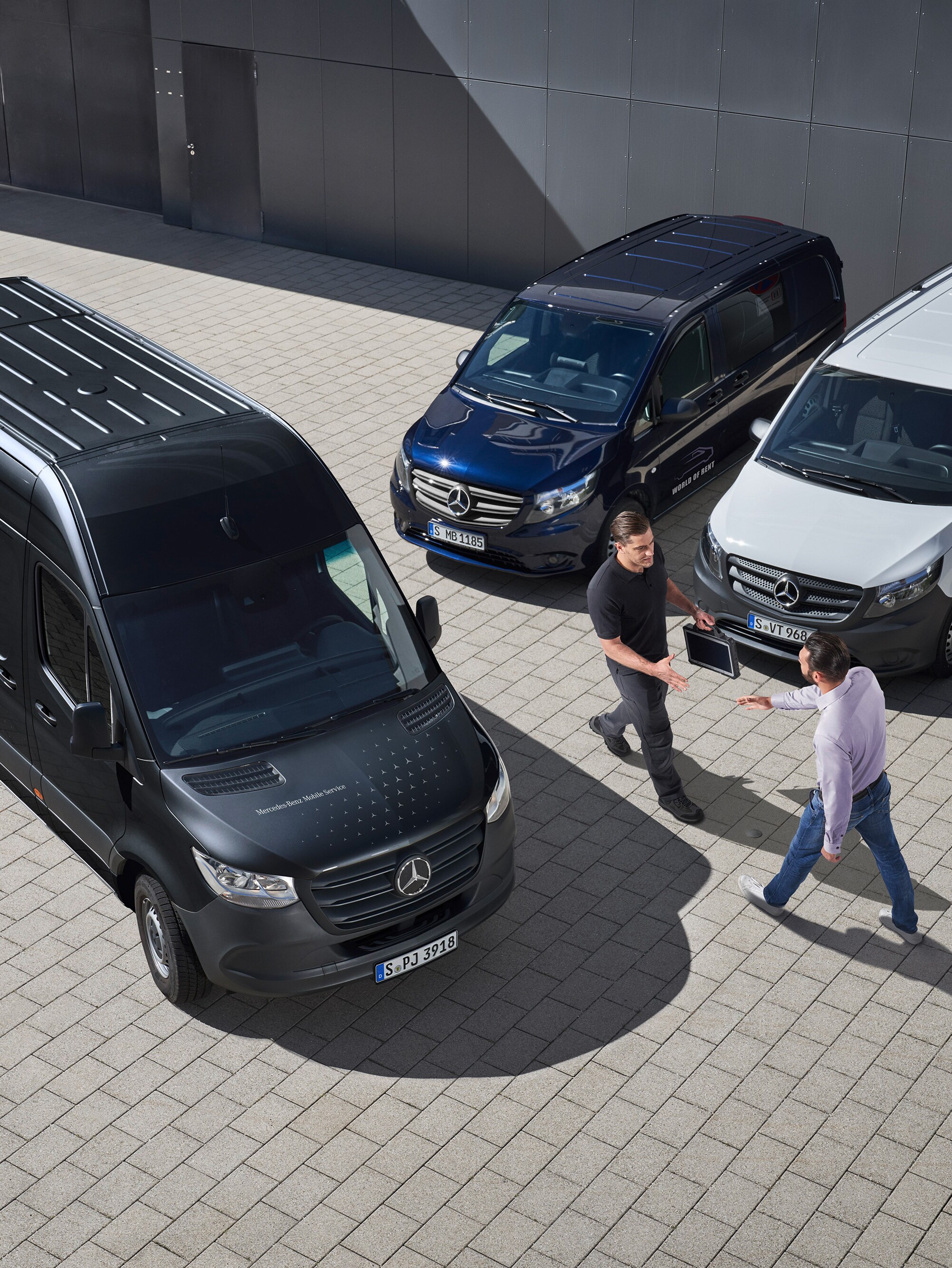 Dois homens cumprimentam-se entre veículos comerciais ligeiros Mercedes-Benz.