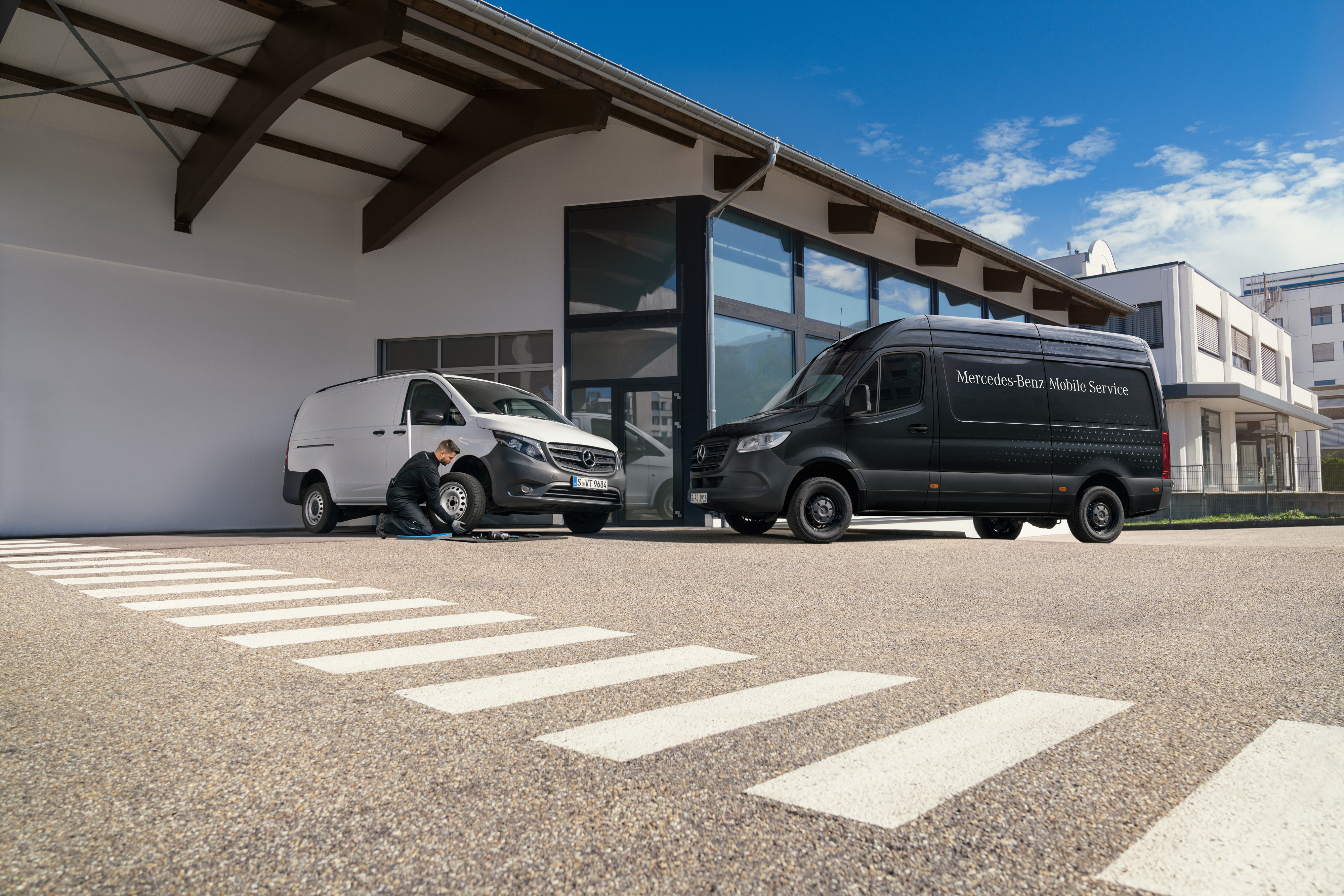Mercedes-Benz | Serviço móvel | Sistema de travagem Um técnico muda um pneu de um veículo comercial ligeiro Mercedes-Benz Vito branco em frente a uma sala de exposições.