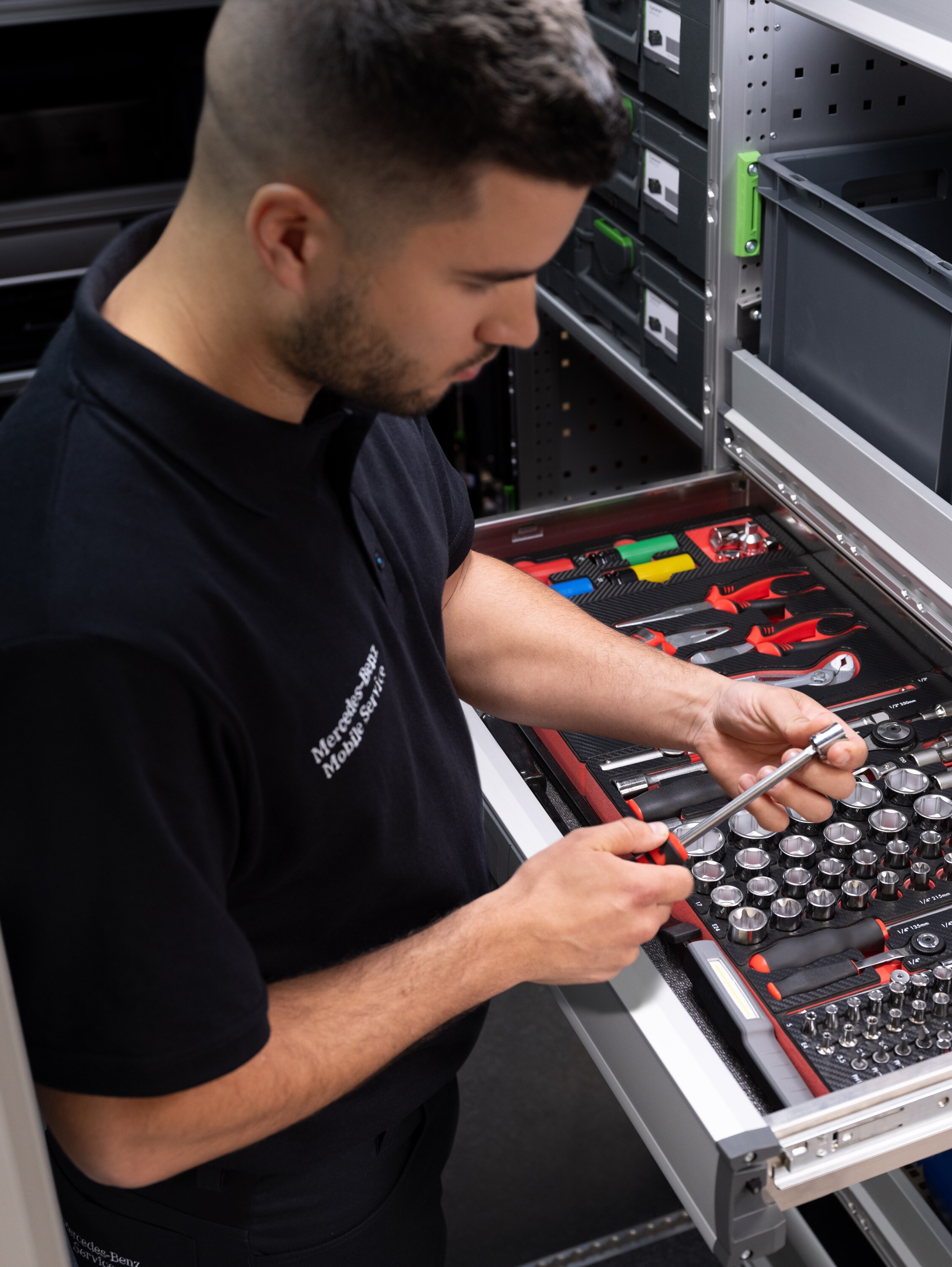 Um técnico seleciona um item de uma gaveta cheia de ferramentas.