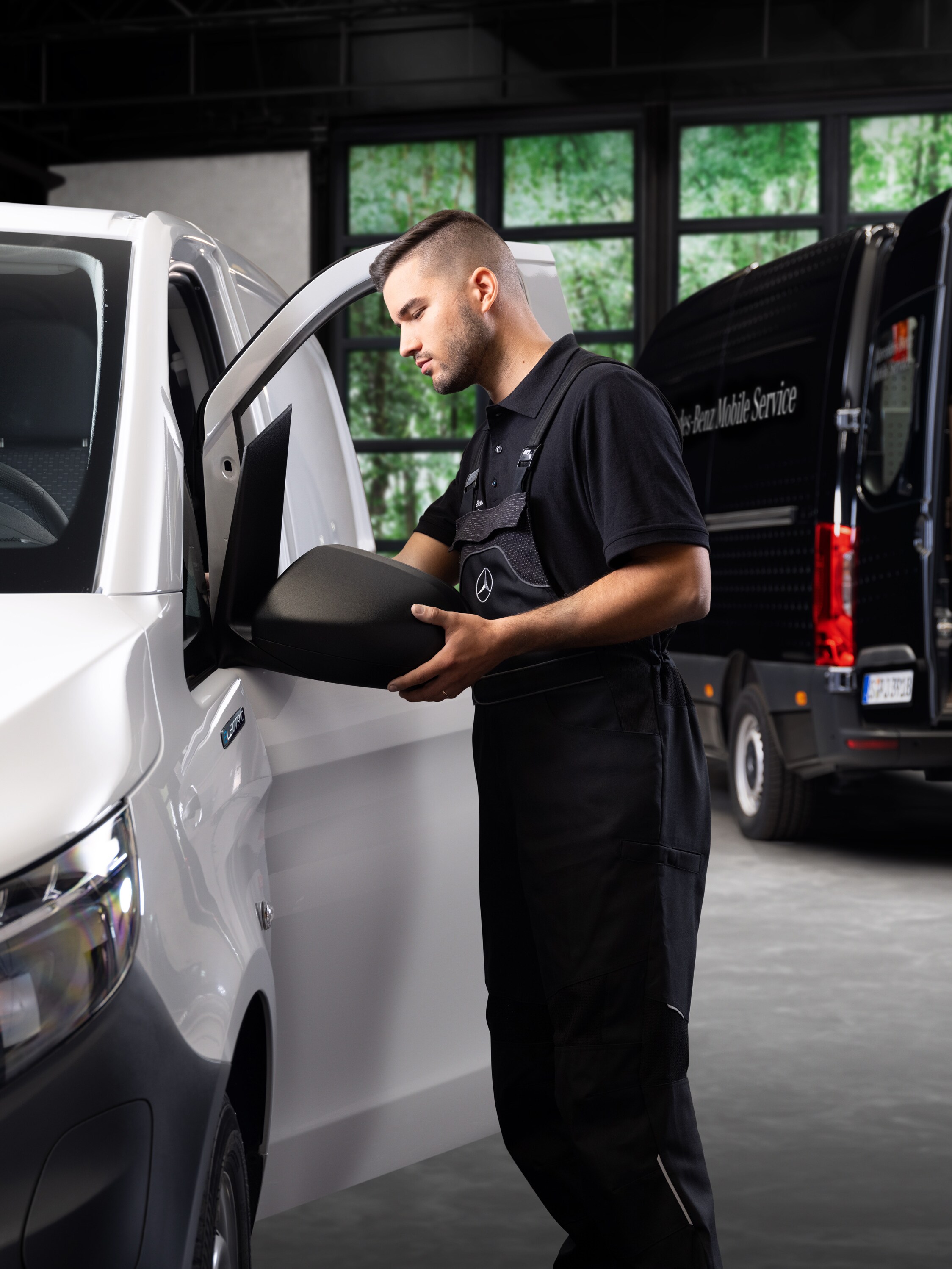 Um técnico substitui um espelho exterior de um veículo comercial ligeiro Mercedes-Benz Vito branco.