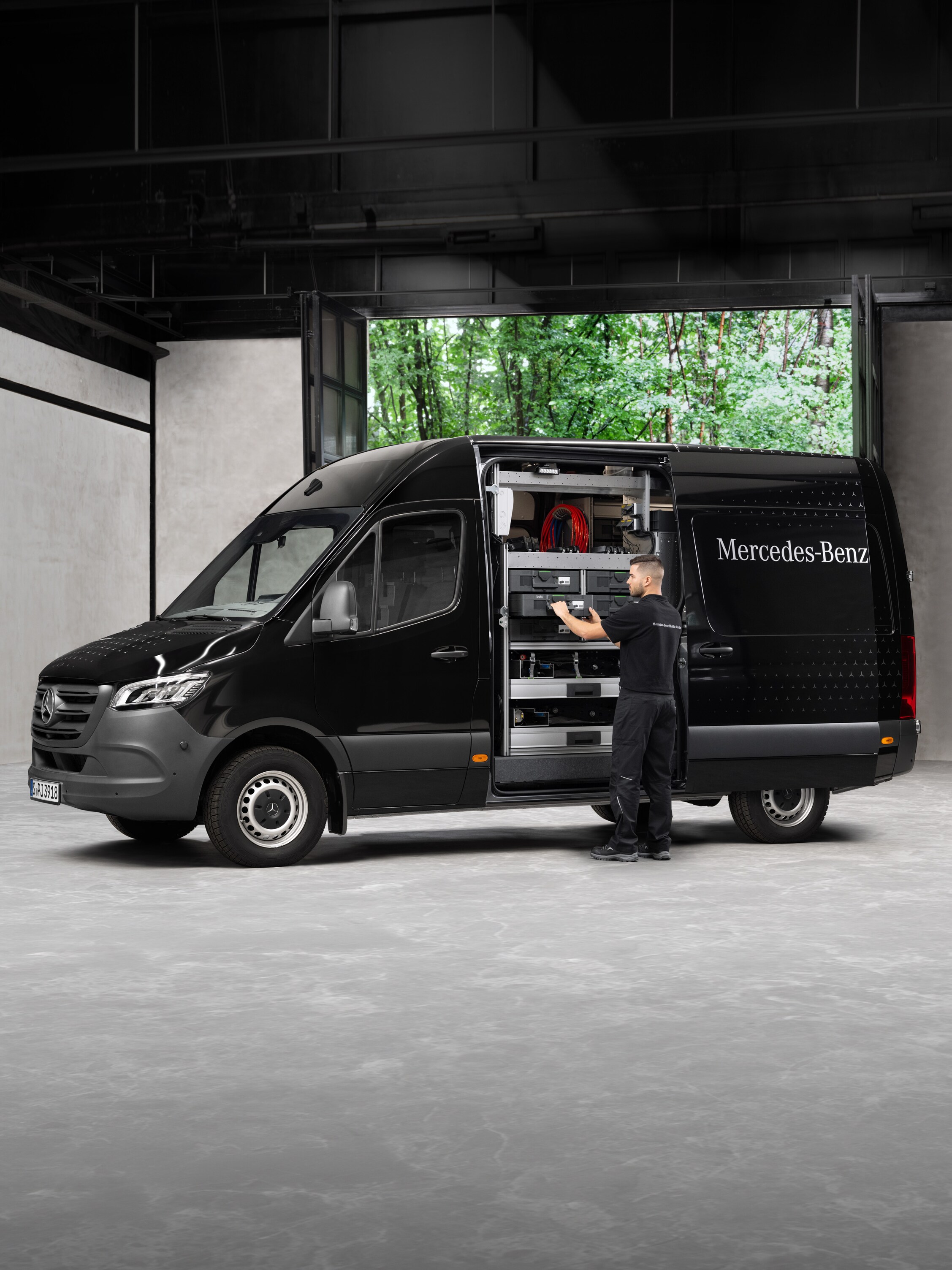 Um técnico retira ferramentas de um veículo comercial ligeiro Mercedes-Benz Sprinter preto.