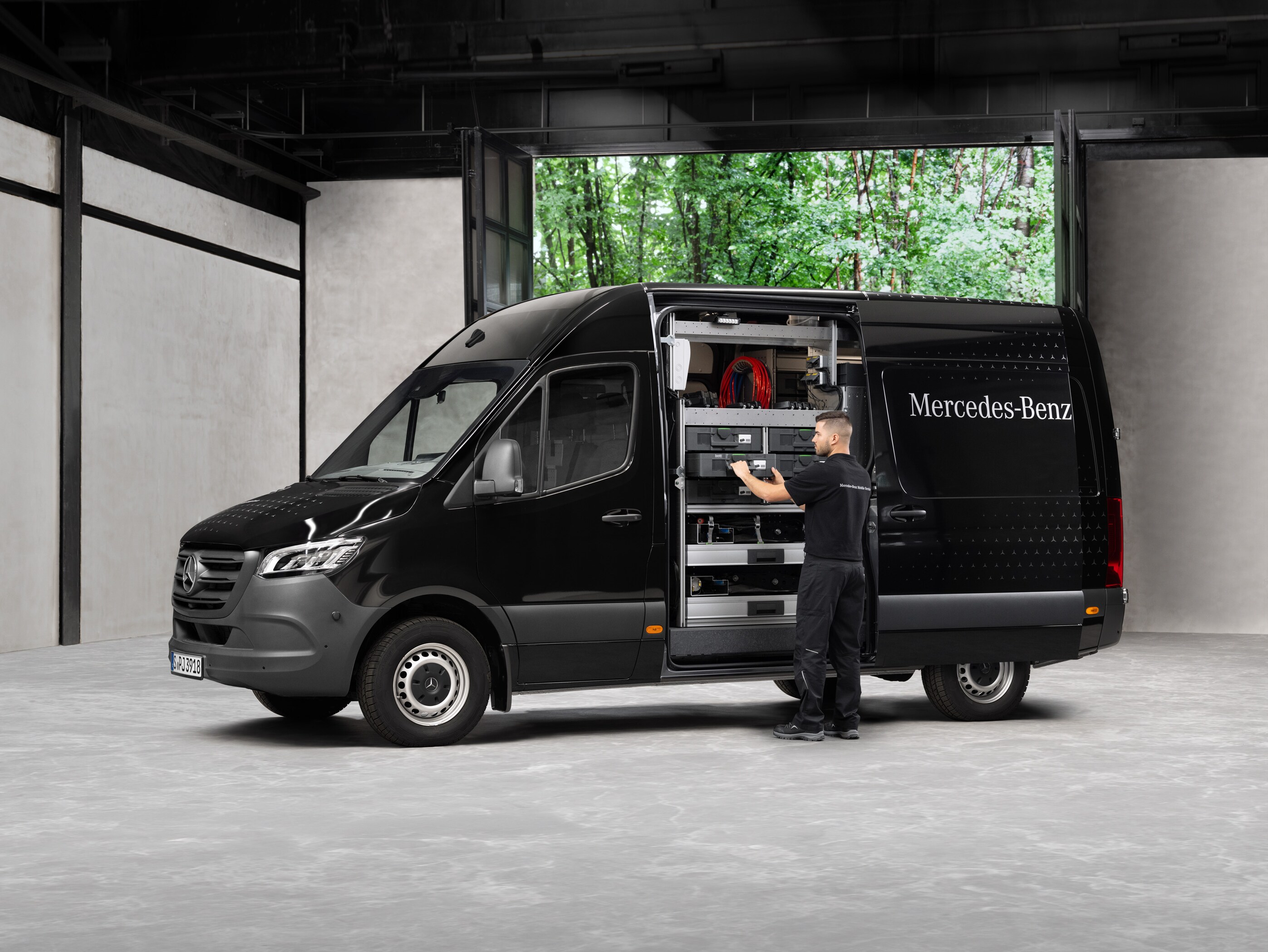Um técnico retira ferramentas de um veículo comercial ligeiro Mercedes-Benz Sprinter preto.