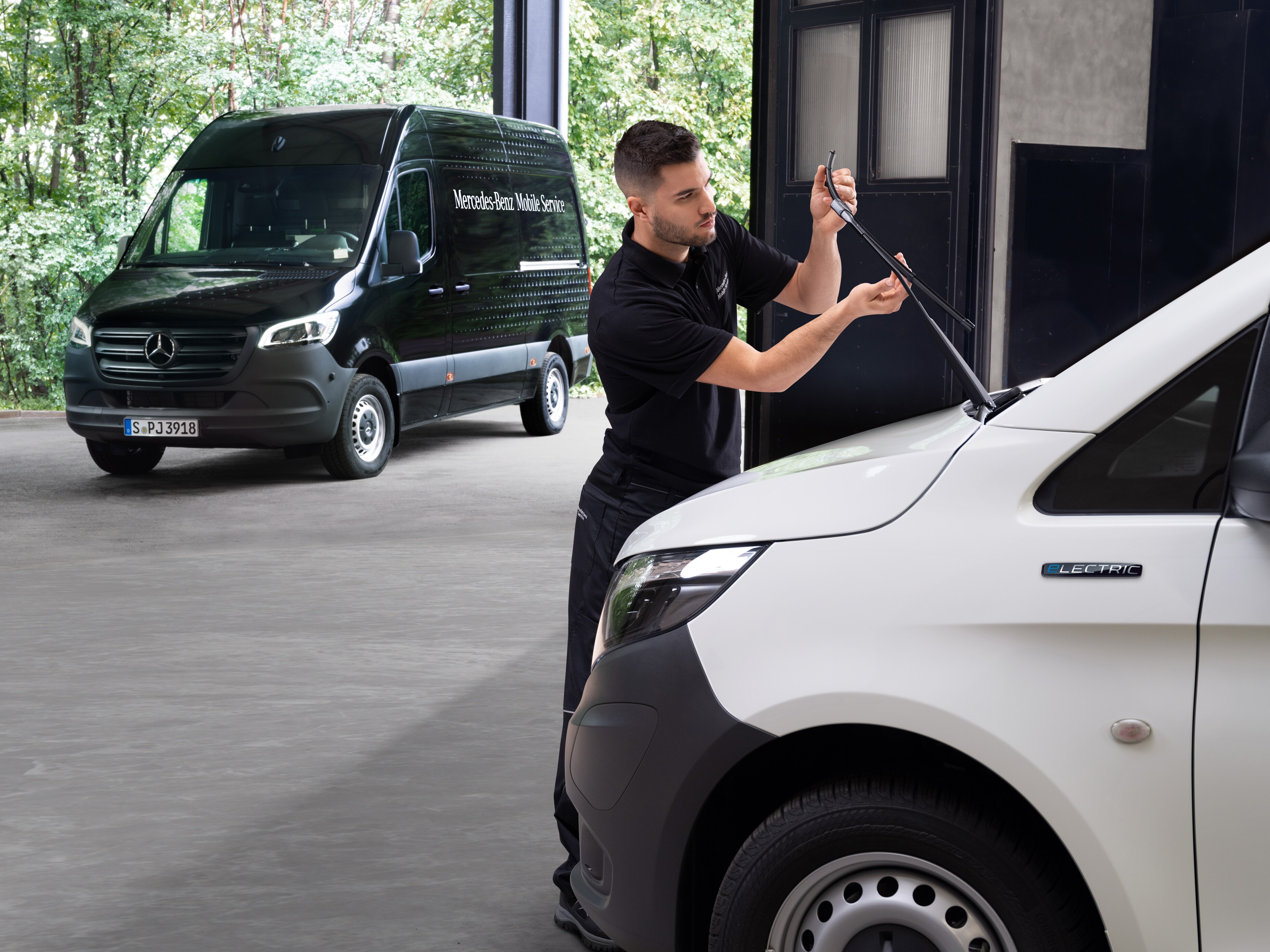 Um técnico muda as escovas do limpa-vidros de um veículo comercial ligeiro Mercedes-Benz Vito branco.