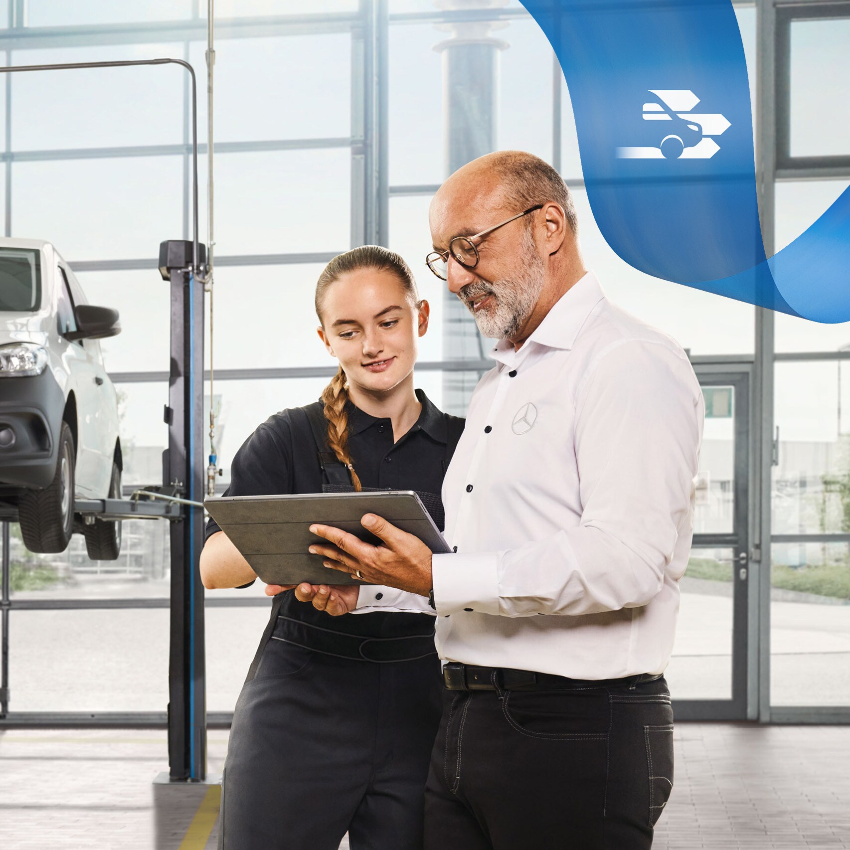 Dois funcionários discutem o serviço de veículos comerciais ligeiros num veículos comerciais ligeiros Mercedes-Benz levantado na oficina.