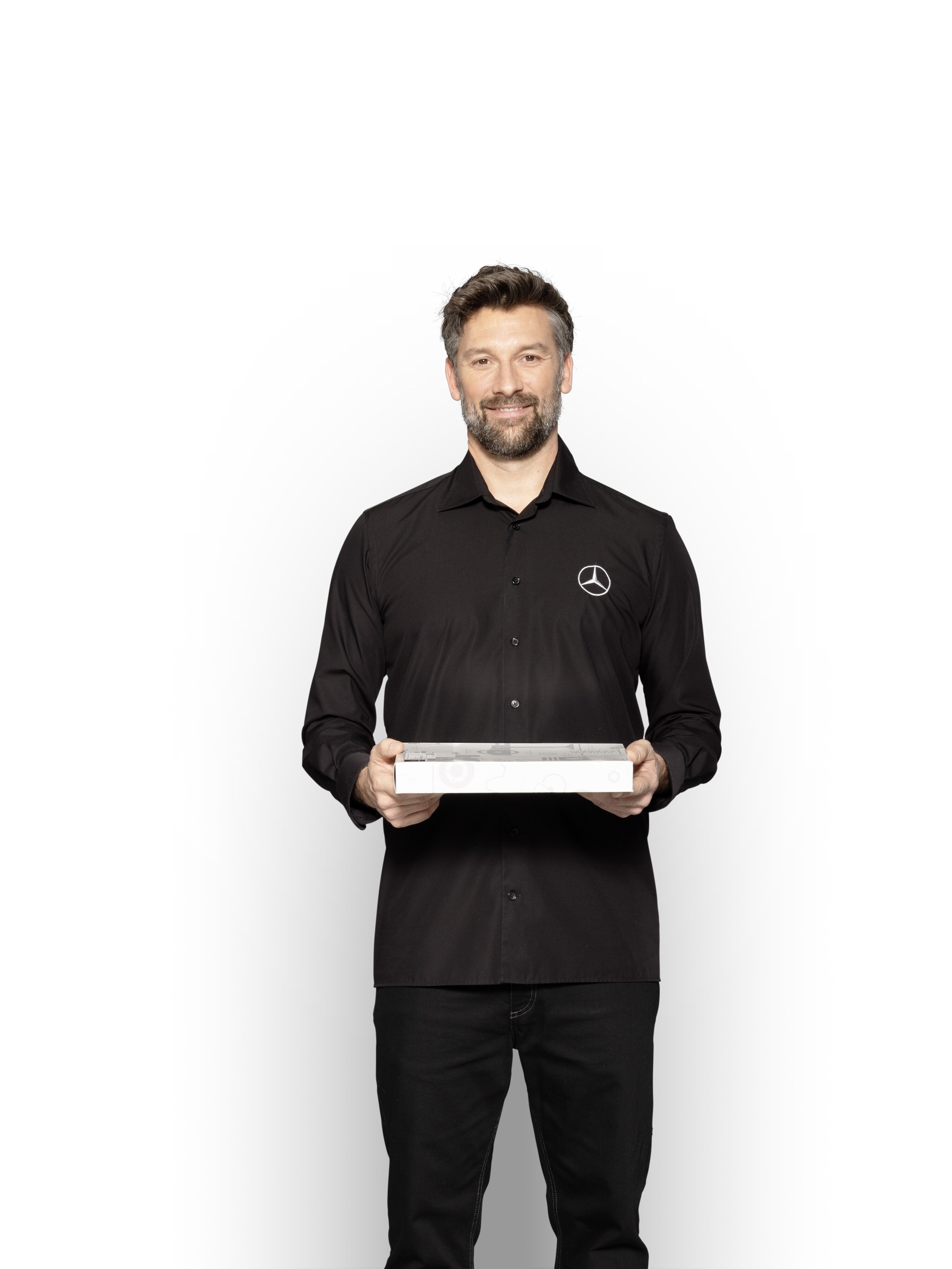 Técnico interno da Mercedes-Benz com uma caixa nas mãos para mostrar Peças Originais Mercedes-Benz.