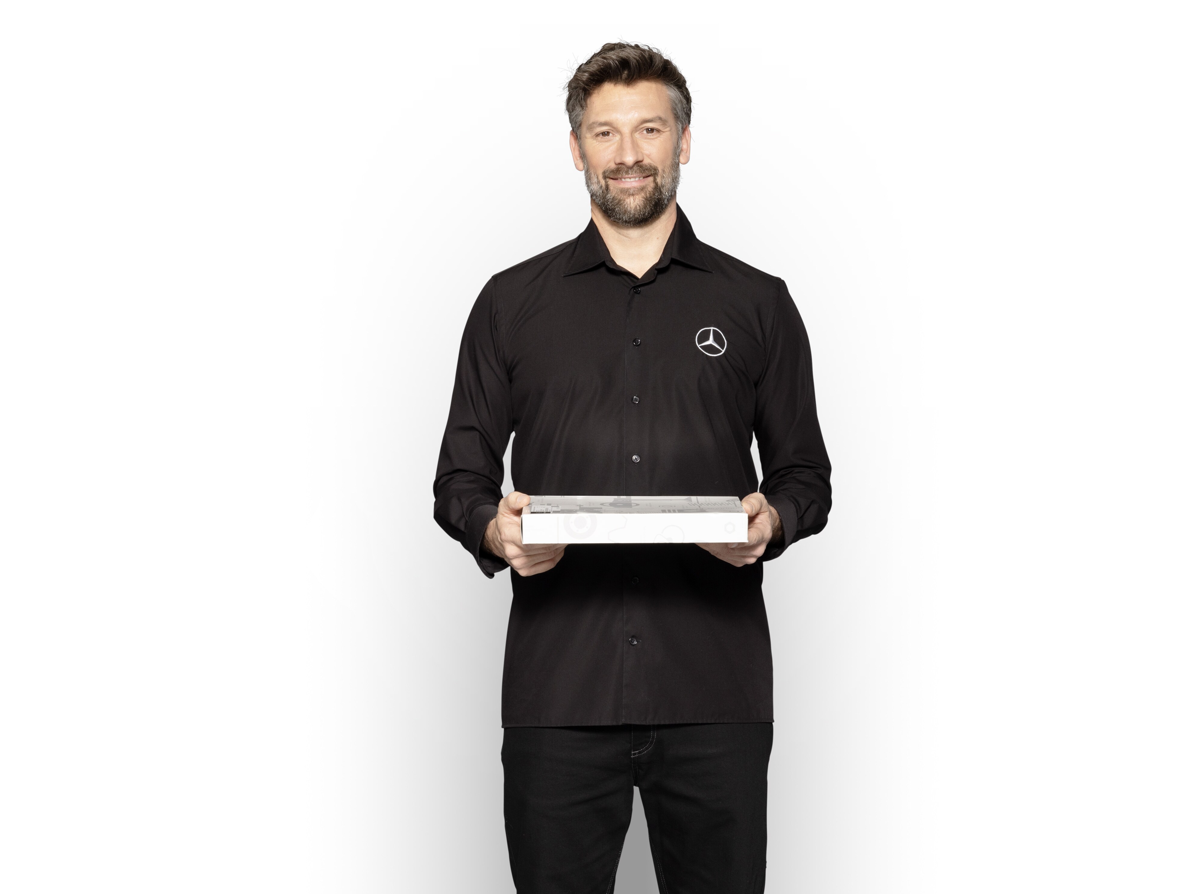 Técnico interno da Mercedes-Benz com uma caixa nas mãos para mostrar Peças Originais Mercedes-Benz.