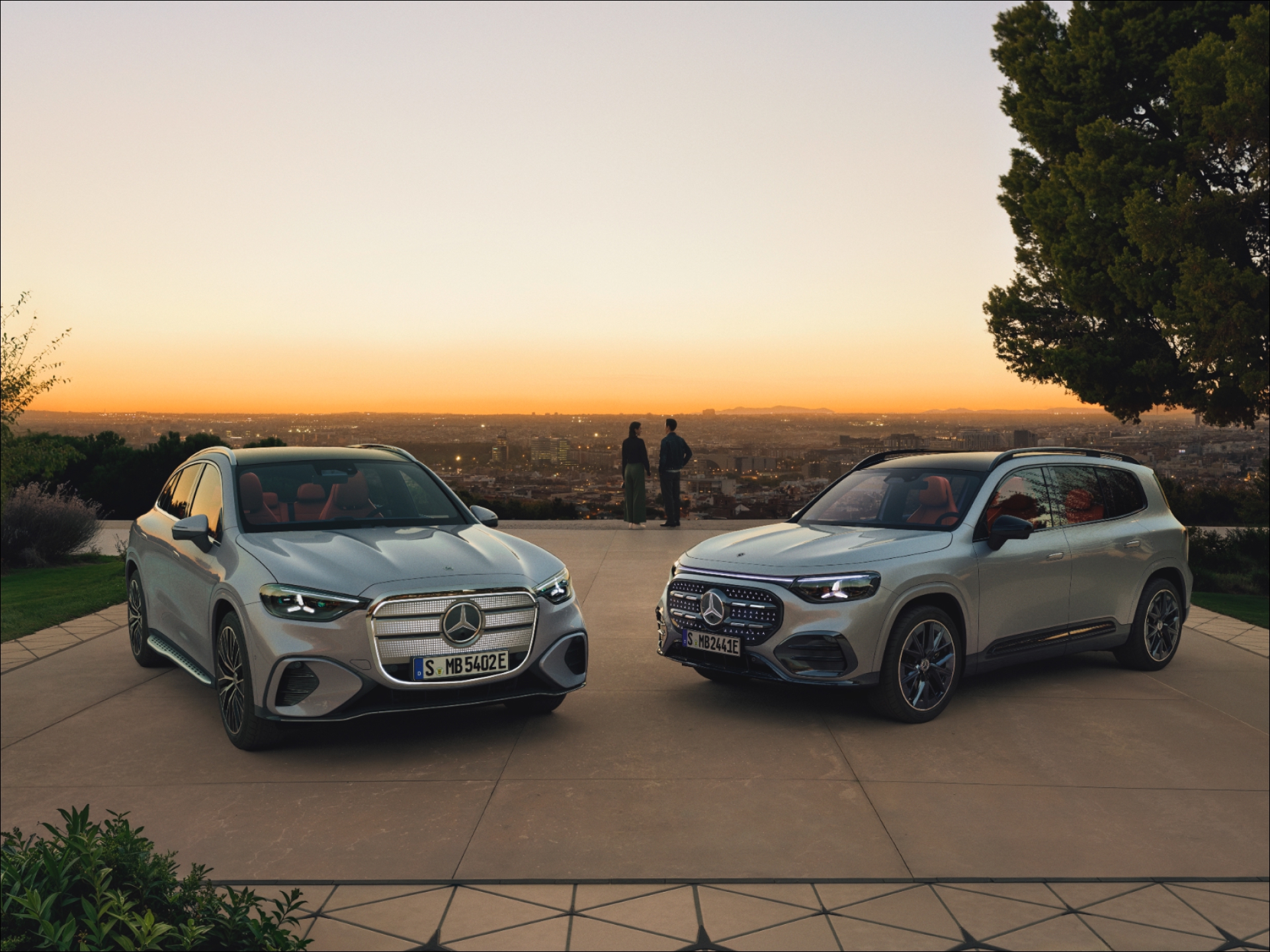 GLC y GLB Eléctricos | Mercedes-Benz Visual del GLC y GLB 100% Eléctricos de Mercedes-Benz en el mirador de una ciudad al atardacer