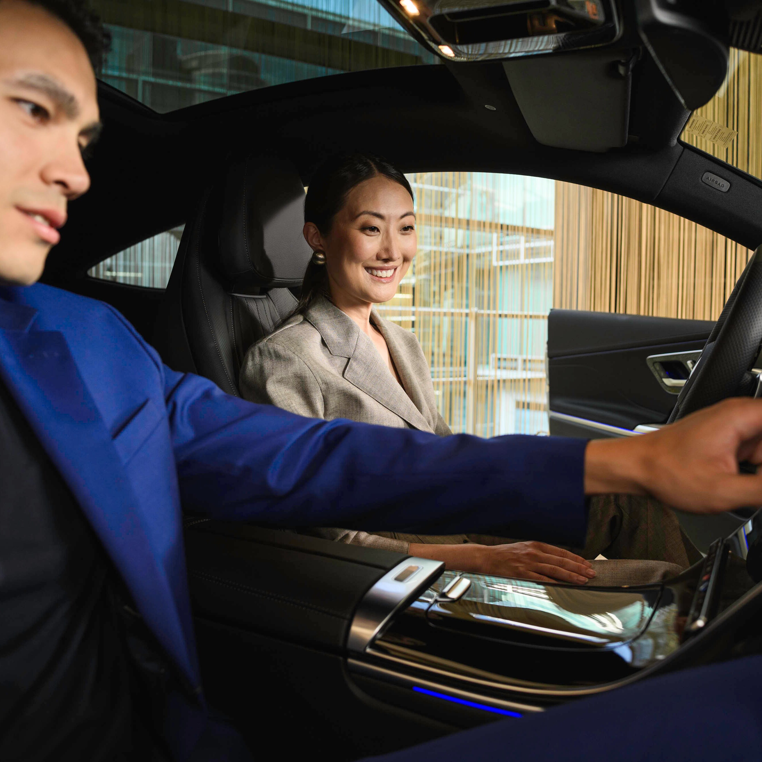 Duas pessoas dentro de um Mercedes-Benz, a mexer no painel de control.